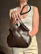 Mature woman with a Charlotte Crossbody from Ulla Johnson luxury woven Italian leather handbag rendered in a elegant neutral matte chocolate brown that easily coordinates with everything