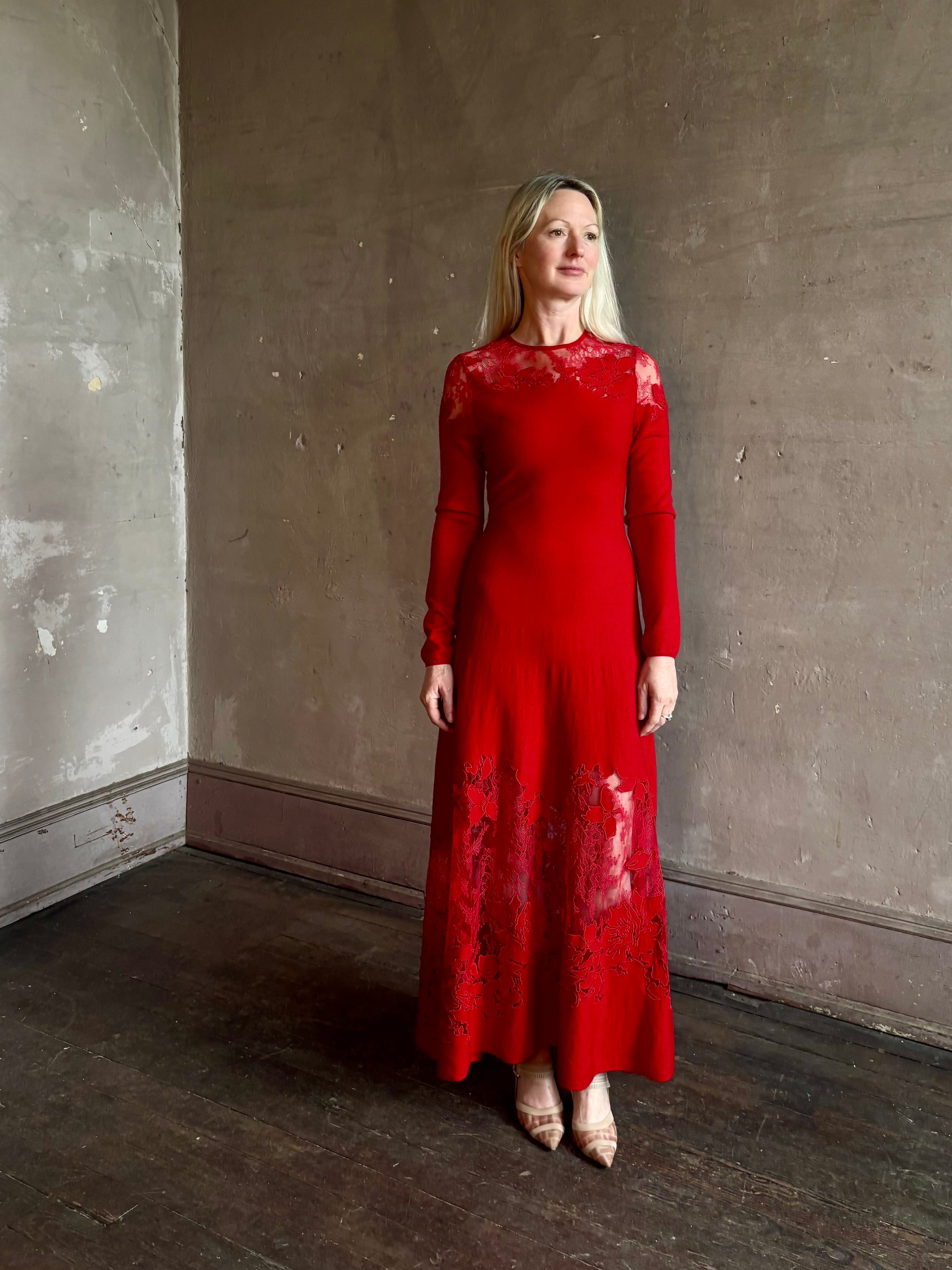 Mature woman wearing designer Ulla Johnson's Clemence LS Lace maxi Dress in Cerise red virgin wool knit A-line delicate lace at the bodice and hemline striking sophisticated occasion elegance