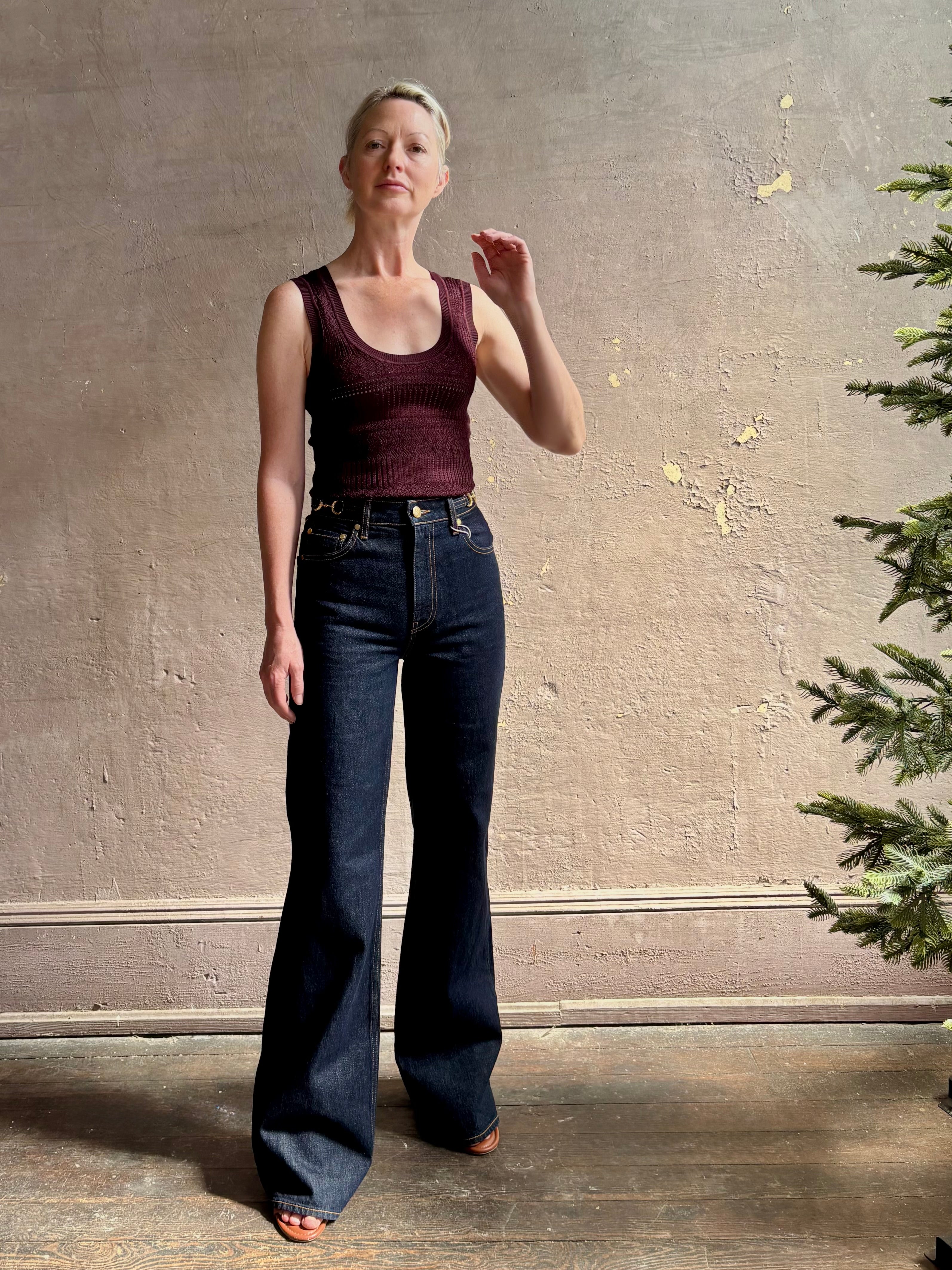 Mature woman wearing designer denim Colette Straight Leg Jean from Ulla Johnson offering American-made craftsmanship to a clean, timeless, and thoroughly modern everyday silhouette rendered in a sophisticated dark wash and crafted from 100% cotton with twisted buckle detail at waistband