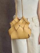 Image of woman holding designer ULLA JOHNSON Charlotte Crossbody handbag in neutral yellow woven leather