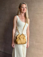 Image of woman wearing designer ULLA JOHNSON Charlotte Crossbody handbag in neutral yellow woven leather