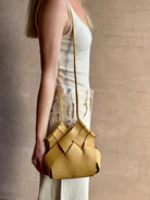 Image of woman wearing designer ULLA JOHNSON Charlotte Crossbody handbag in neutral yellow woven leather