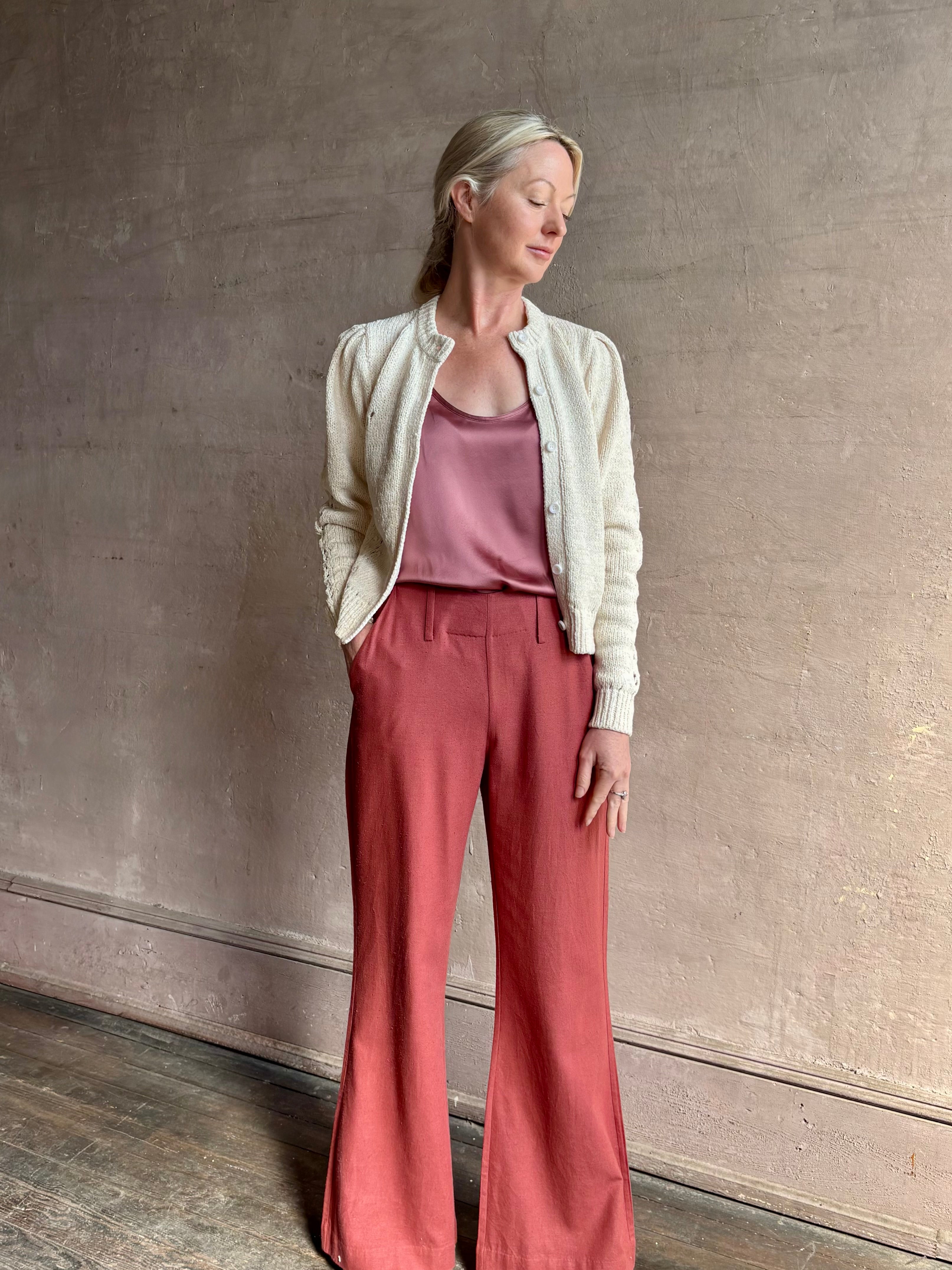 Mature woman wearing the Delphina Long Sleeve Cardigan from Ulla Johnson rendered in a soft off-white  with crew neck, feminine sleeves and button front