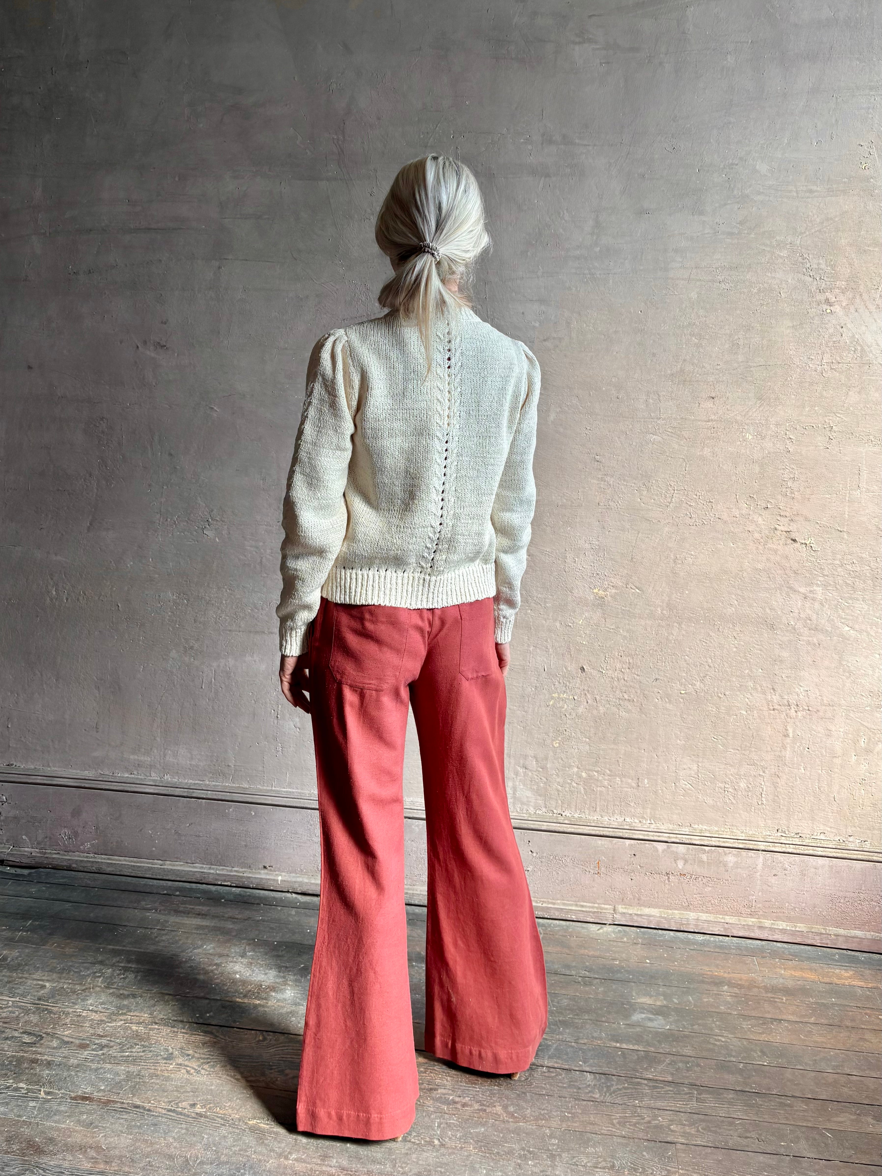 Mature woman wearing the Delphina Long Sleeve Cardigan from Ulla Johnson rendered in a soft off-white  with crew neck, feminine sleeves and button front