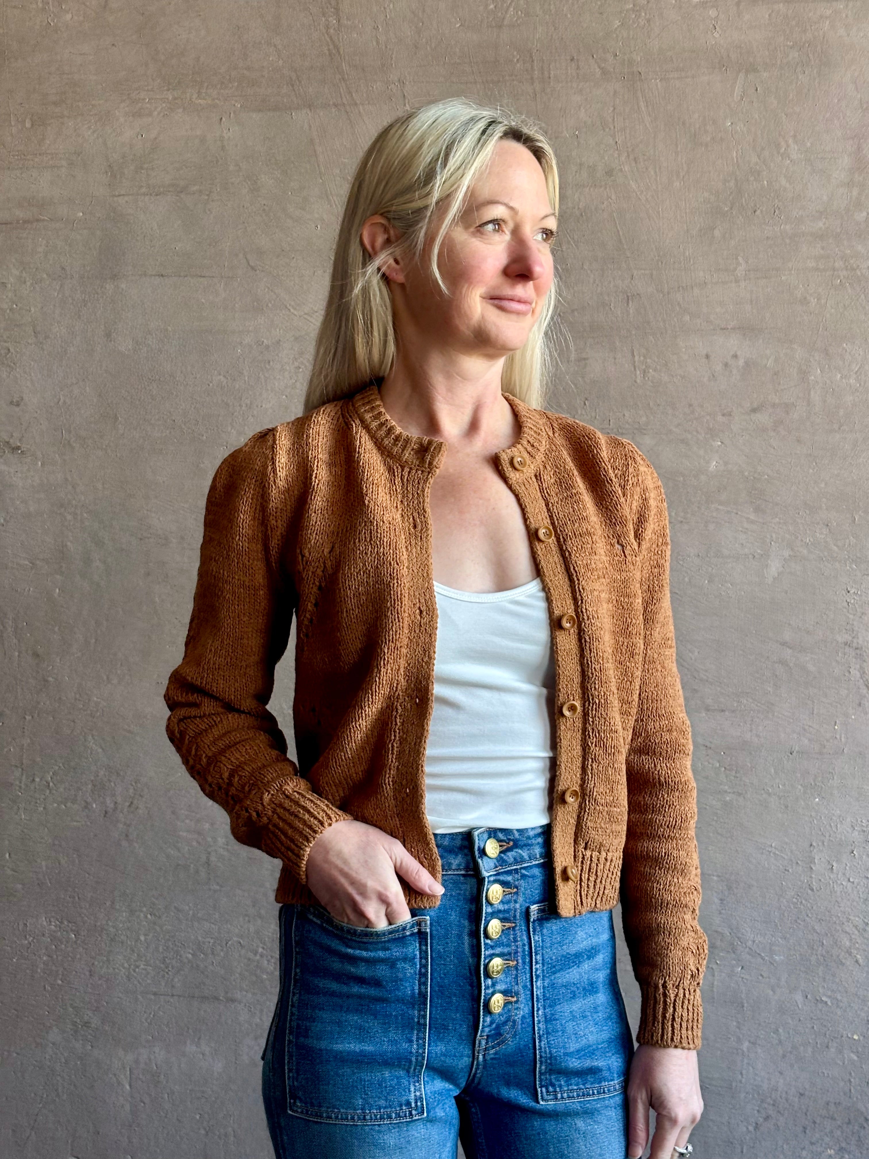 Mature woman wearing the Delphina Long Sleeve women's designer Cardigan from Ulla Johnson rendered in an umber hue with a crew neck and button front