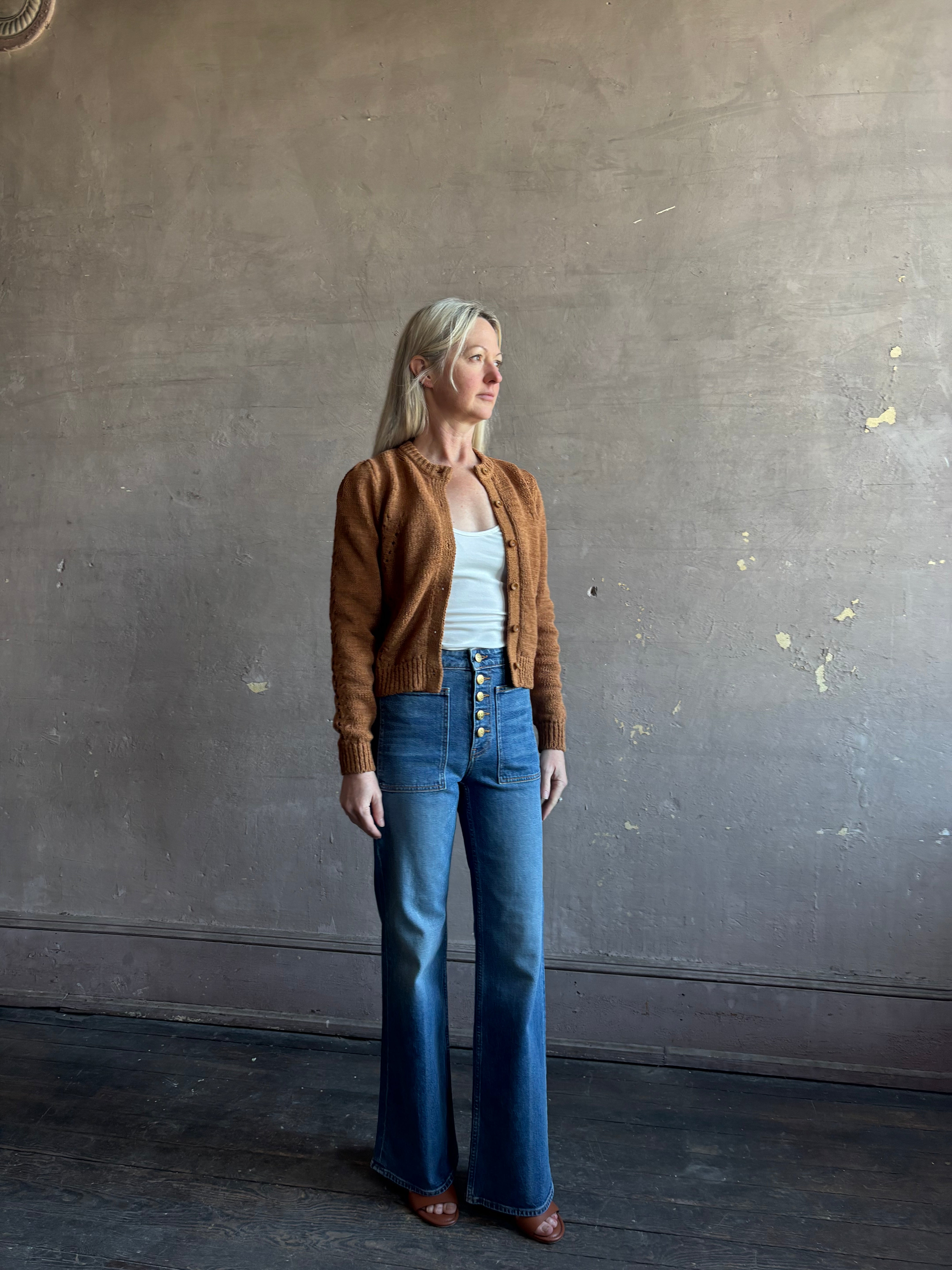 Mature woman wearing the Delphina Long Sleeve women's designer Cardigan from Ulla Johnson rendered in an umber hue with a crew neck and button front