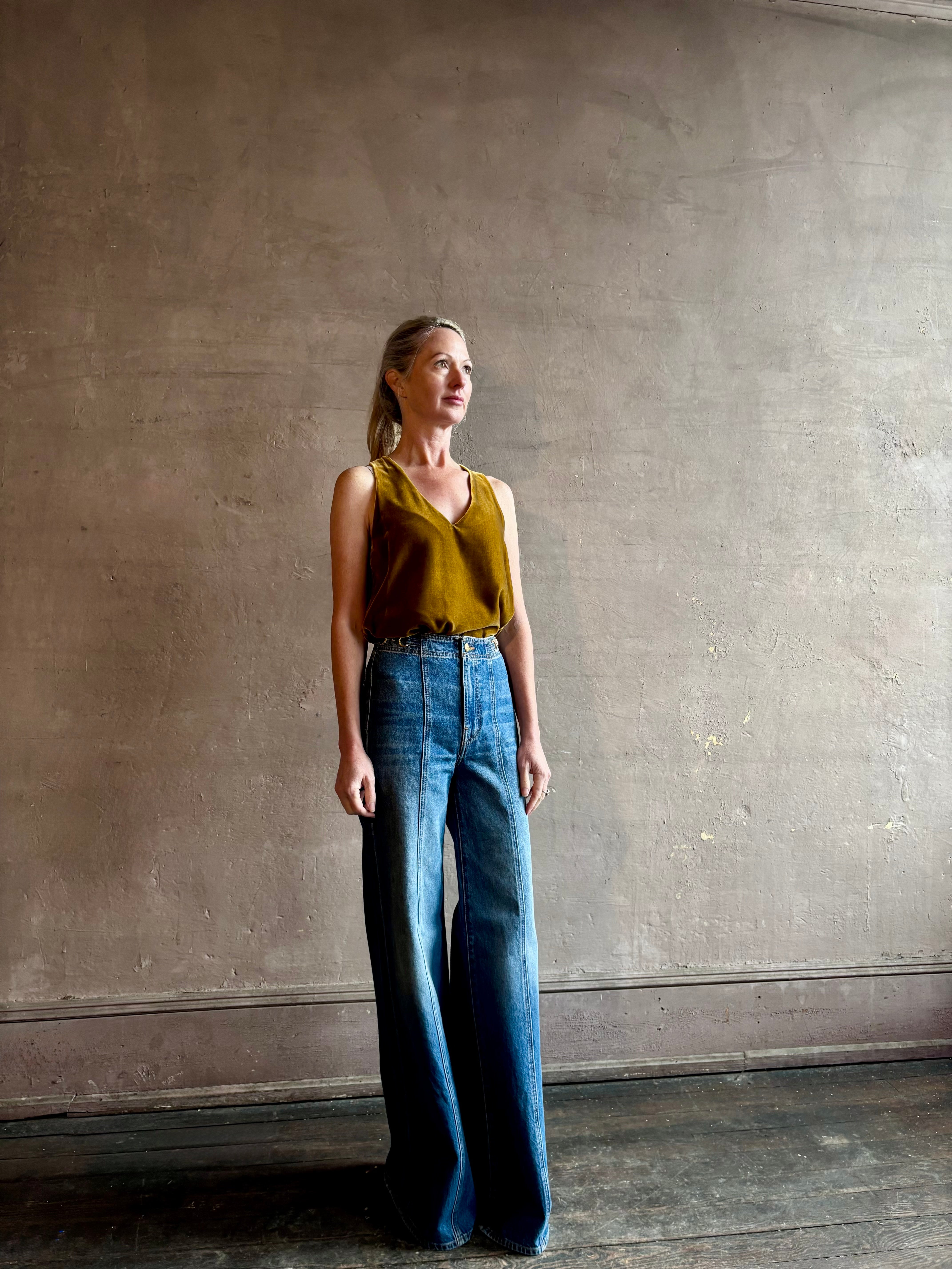Mature woman wearing designer Ulla Johnson delphine wide leg high rise cotton rigid denim with gold buckle detail zip closure