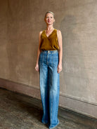 Mature woman wearing designer Ulla Johnson delphine wide leg high rise cotton rigid denim with gold buckle detail zip closure