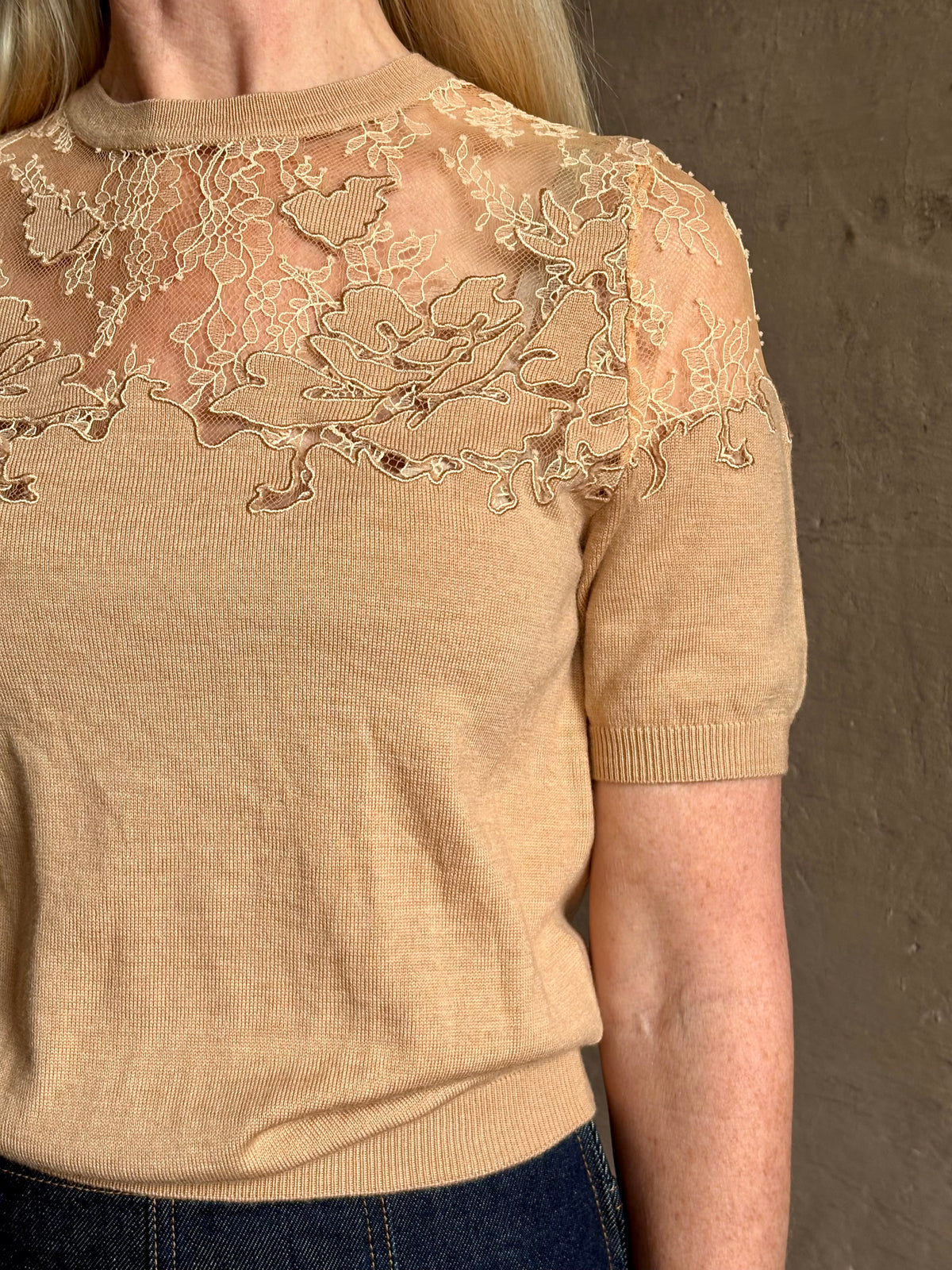 Mature woman wearing Ulla Johnson's Ella Short Sleeve Lace merino wool knit Top in Almond delicate lace detailing at the shoulders classic elegance