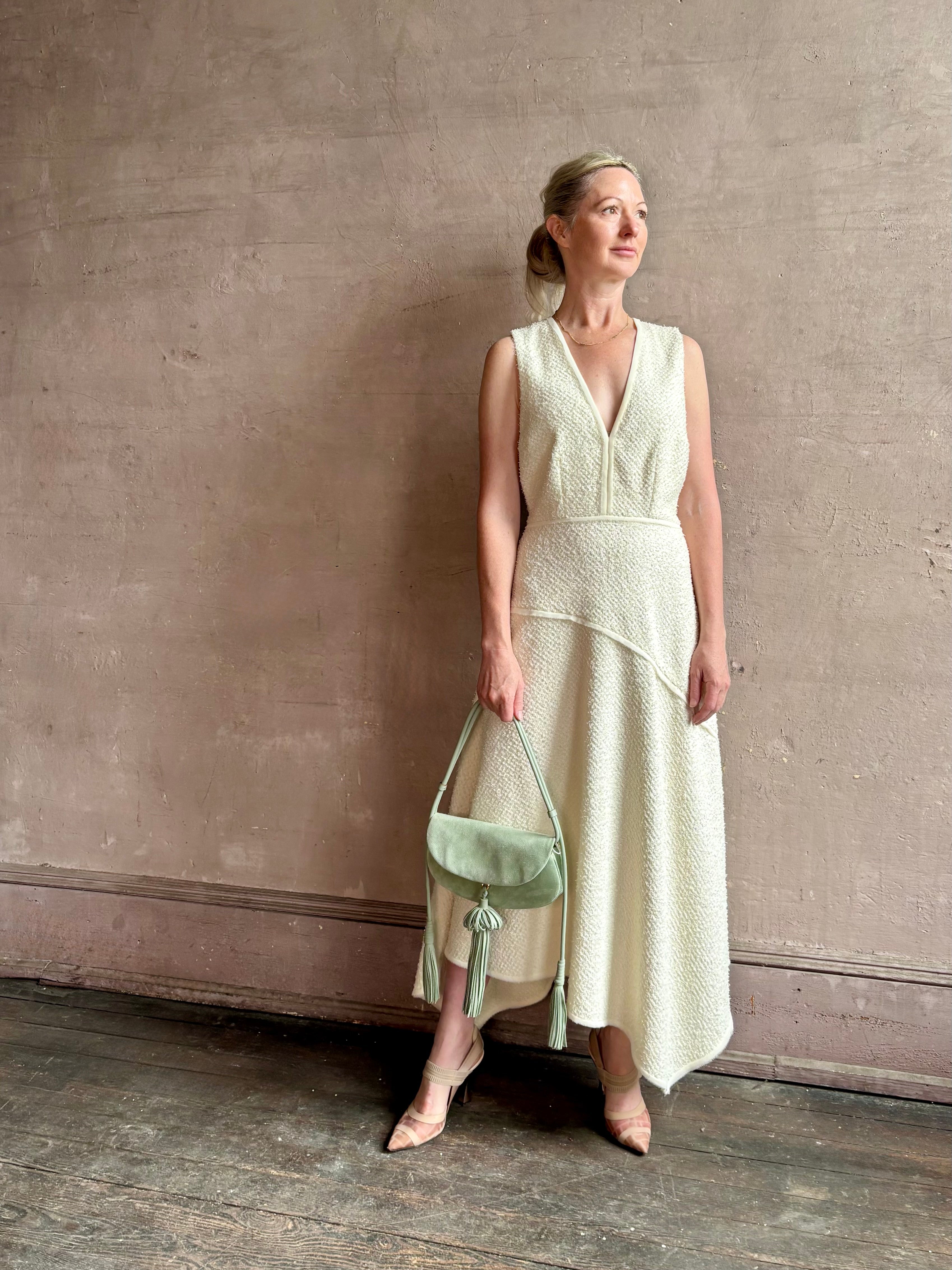 Woman wearing Ulla Johnson Florence Dress in textured off-white cotton blend with a v-neckline asymmetrical hem
