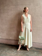Woman wearing Ulla Johnson Florence Dress in textured off-white cotton blend with a v-neckline asymmetrical hem
