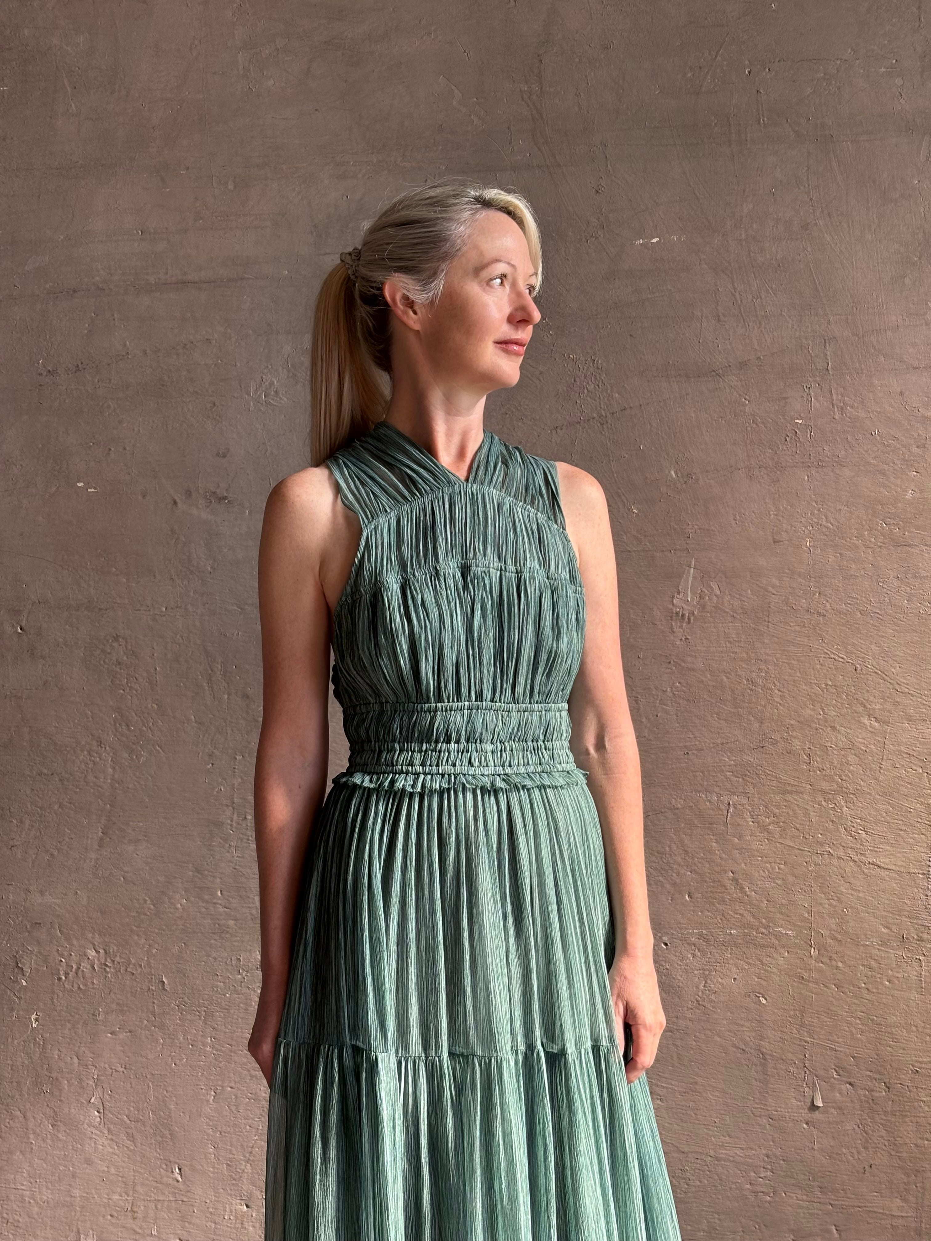 Woman wearing Freesia Gown from Ulla Johnson rendered in a soft green and crafted from luxurious silk crinkle chiffon with low back and flexible waistband