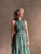 Woman wearing Freesia Gown from Ulla Johnson rendered in a soft green and crafted from luxurious silk crinkle chiffon with low back and flexible waistband