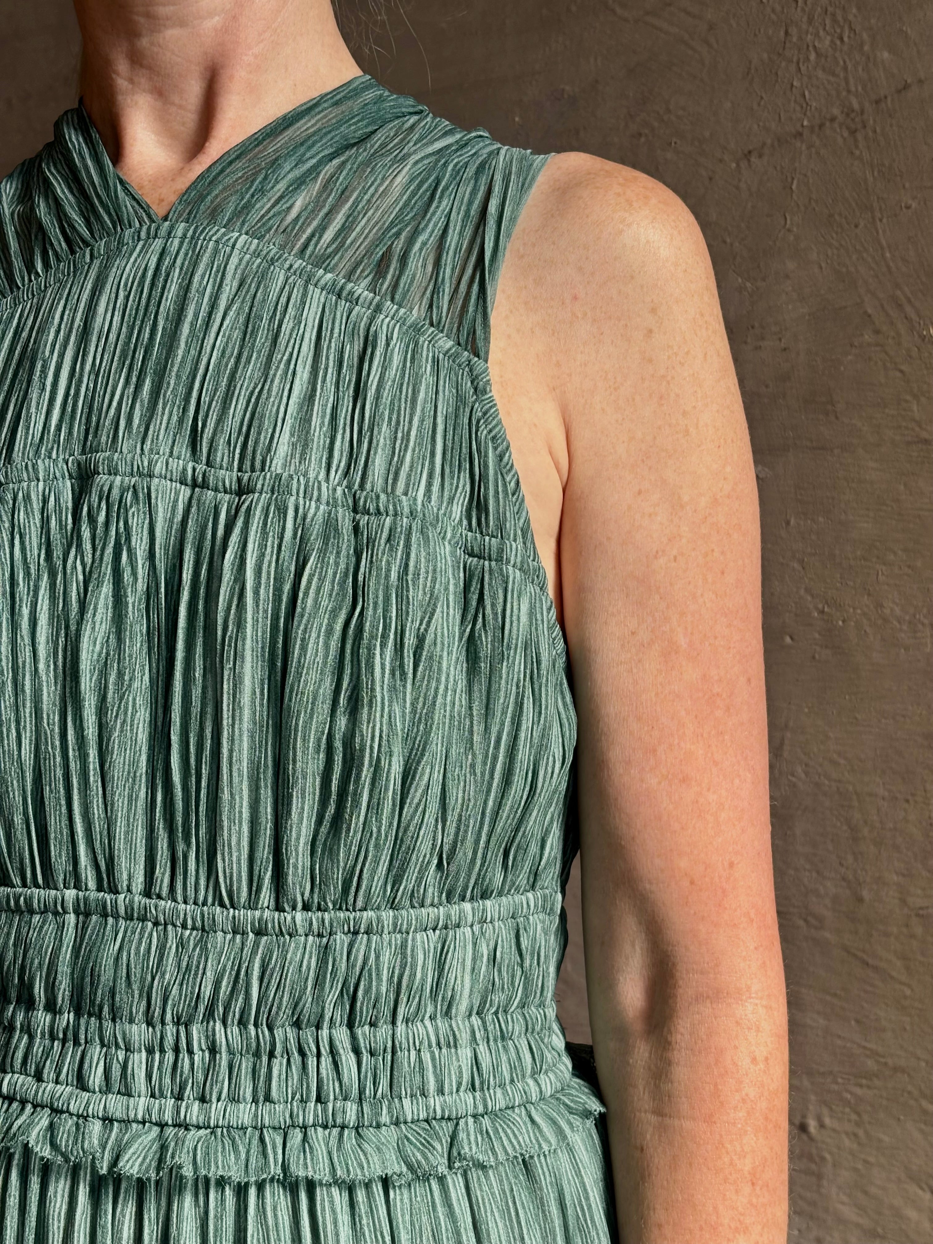 Woman wearing Freesia Gown from Ulla Johnson rendered in a soft green and crafted from luxurious silk crinkle chiffon with low back and flexible waistband