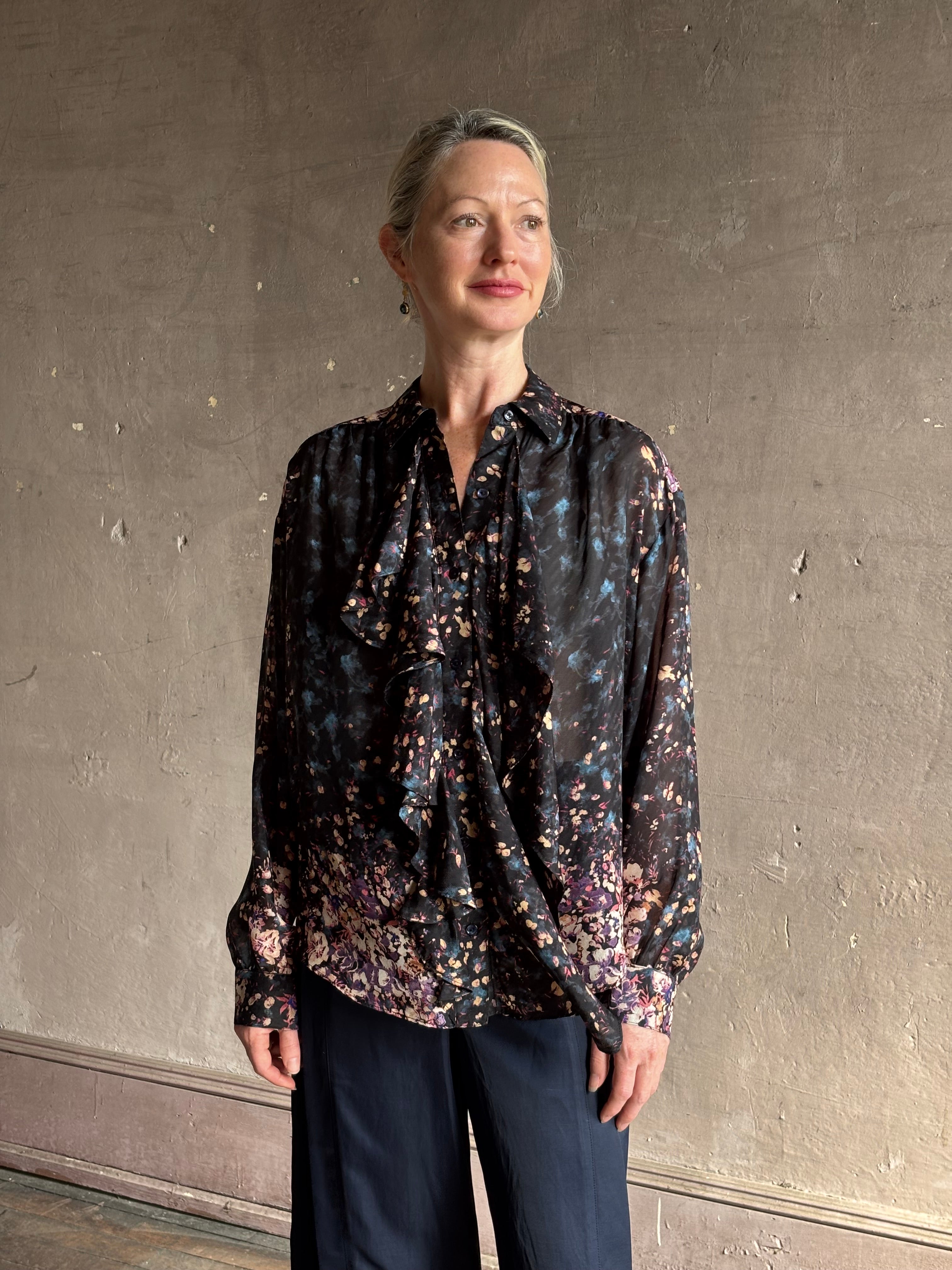 woman wearing designer Ulla Johnson long-sleeve black silk blouse subtle floral print collared button front ruffle