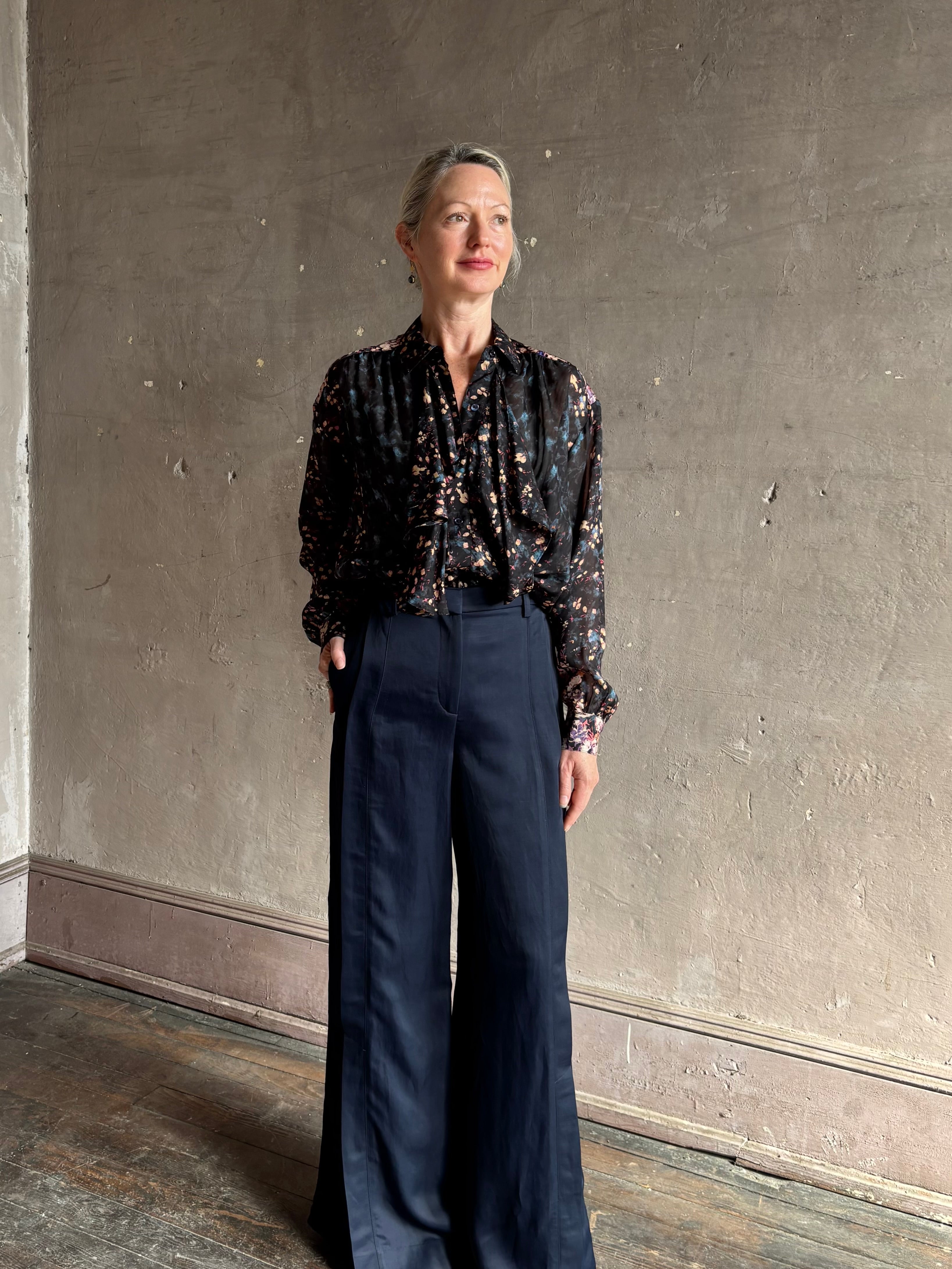 woman wearing Ulla Johnson long-sleeve black silk blouse subtle floral print collared button front ruffle detail