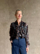 woman wearing designer Ulla Johnson long-sleeve black silk blouse subtle floral print collared button front ruffle