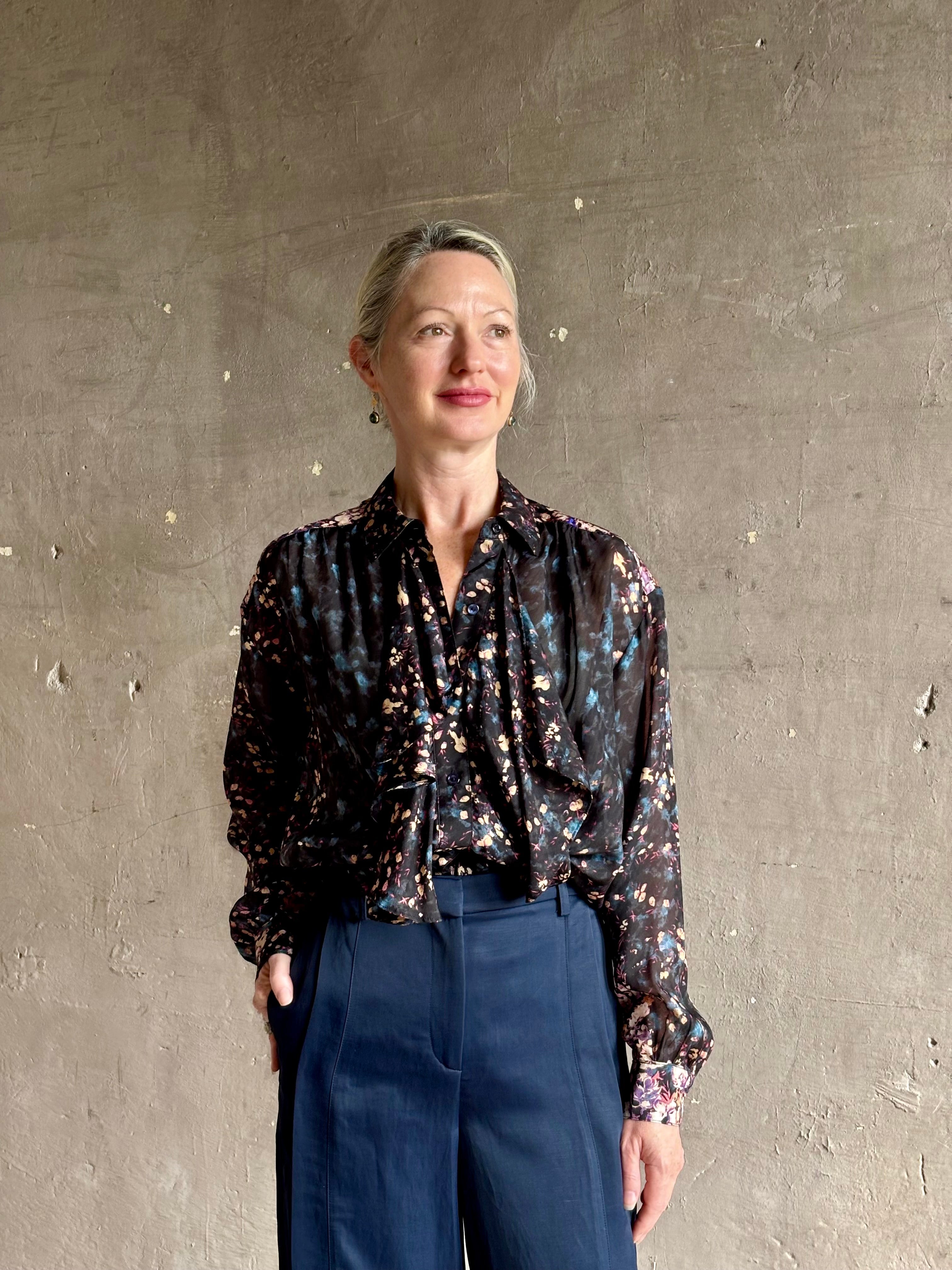 woman wearing designer Ulla Johnson long-sleeve black silk blouse subtle floral print collared button front ruffle