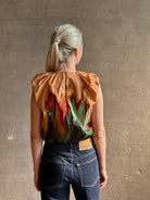 Mature woman wearing Women's designer Gracie sleeveless Cotton Top from Ulla Johnson rendered in a rich abstract Agate print composed of dark green, mint green, burgundy, terra cotta, and sienna and crafted from lightweight cotton poplin