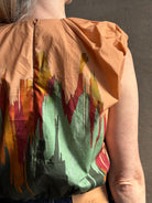 Mature woman wearing Women's designer Gracie sleeveless Cotton Top from Ulla Johnson rendered in a rich abstract Agate print composed of dark green, mint green, burgundy, terra cotta, and sienna and crafted from lightweight cotton poplin
