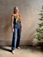 Mature woman wearing Women's designer Gracie sleeveless Cotton Top from Ulla Johnson rendered in a rich abstract Agate print composed of dark green, mint green, burgundy, terra cotta, and sienna and crafted from lightweight cotton poplin