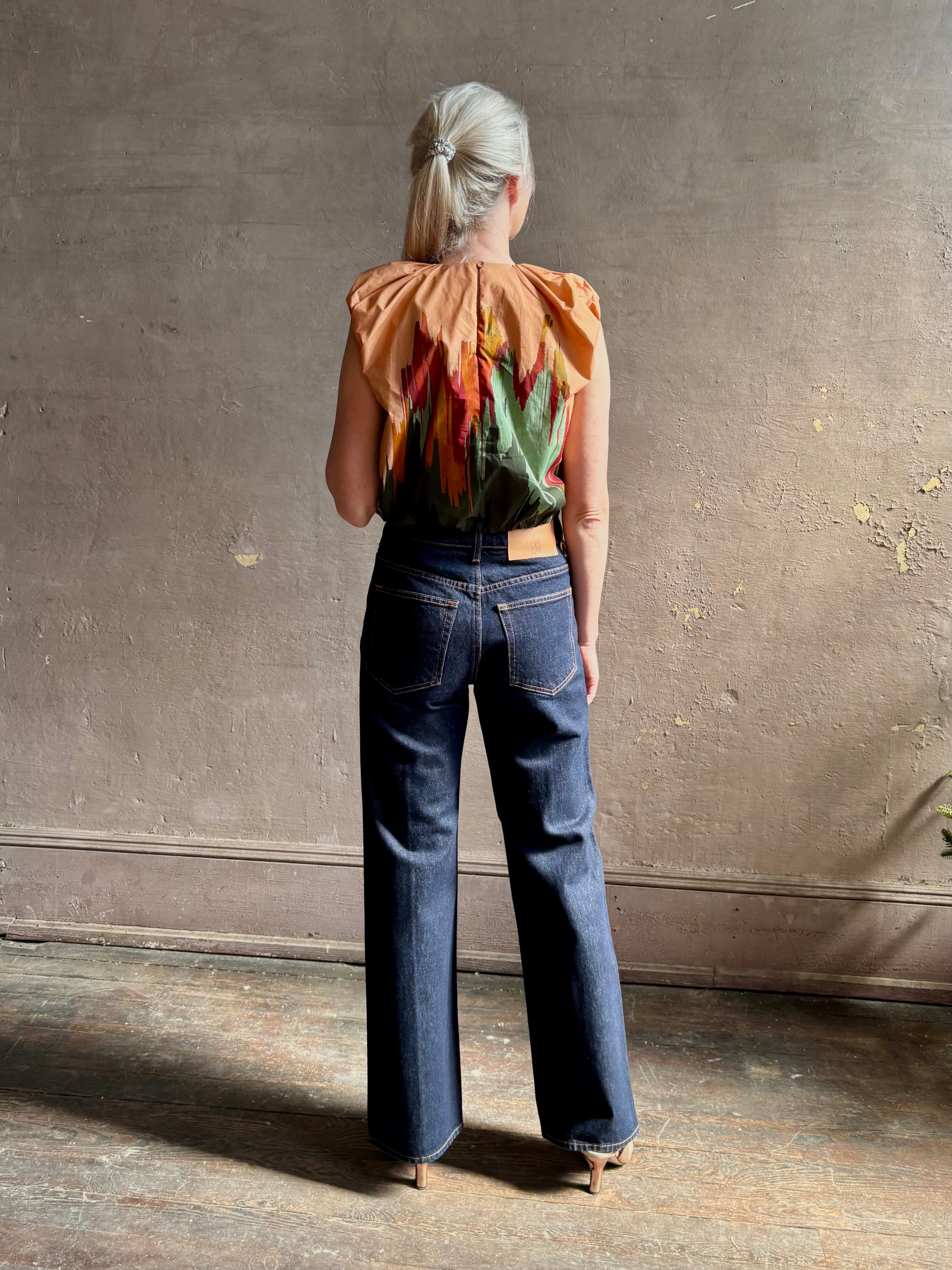 Mature woman wearing Women's designer Gracie sleeveless Cotton Top from Ulla Johnson rendered in a rich abstract Agate print composed of dark green, mint green, burgundy, terra cotta, and sienna and crafted from lightweight cotton poplin