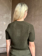 Mature woman wearing designer Ulla Johnson Imara Short Sleeve dark green Sweater with a dimensional open weave