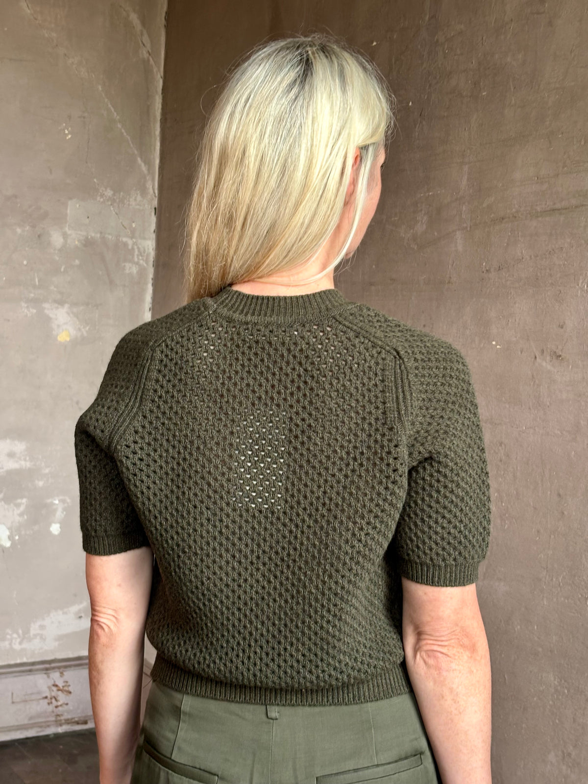 Mature woman wearing designer Ulla Johnson Imara Short Sleeve dark green Sweater with a dimensional open weave