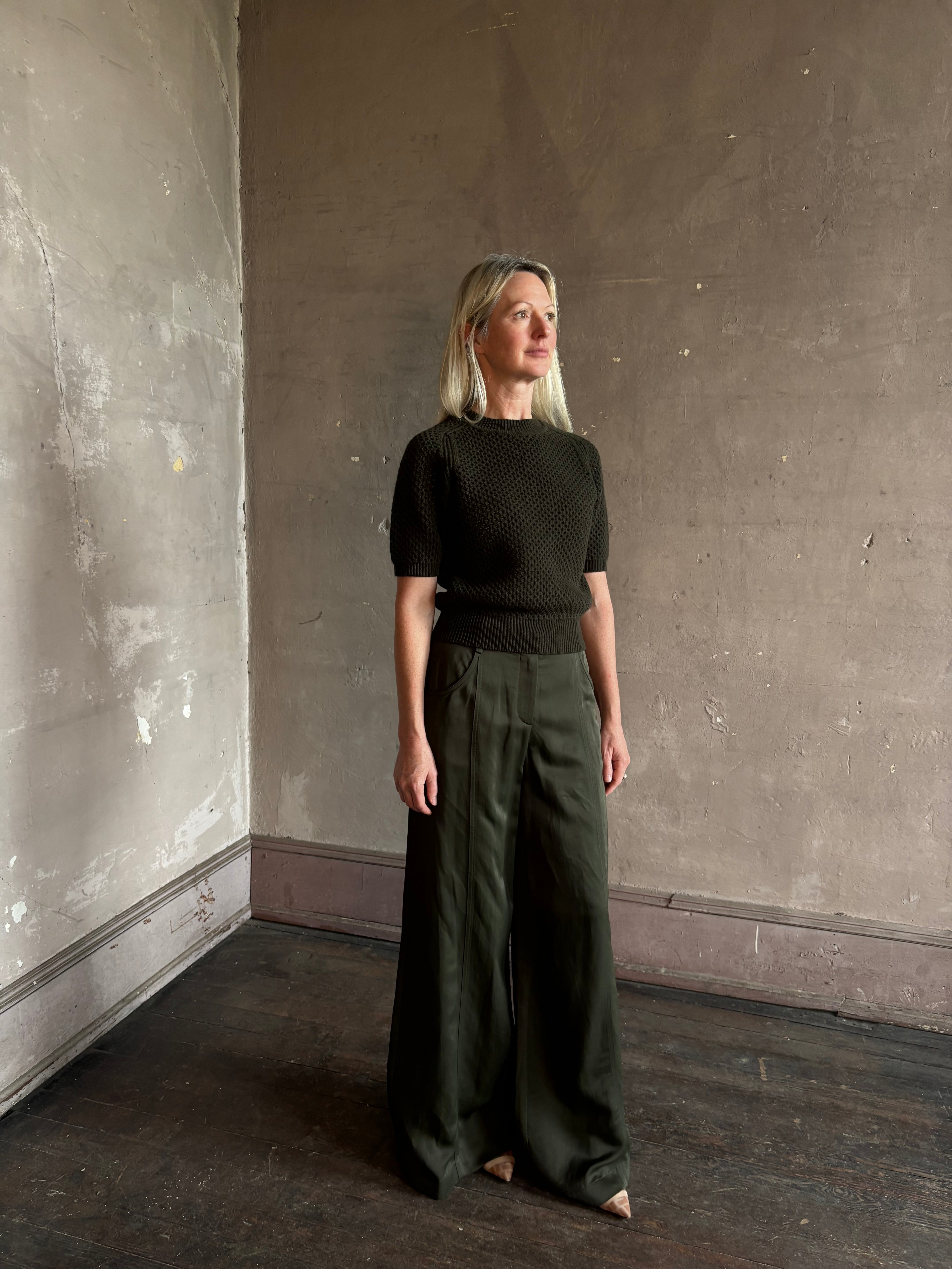 Mature woman wearing designer Ulla Johnson Imara Short Sleeve dark green Sweater with a dimensional open weave