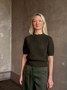 Mature woman wearing designer Ulla Johnson Imara Short Sleeve dark green Sweater with a dimensional open weave