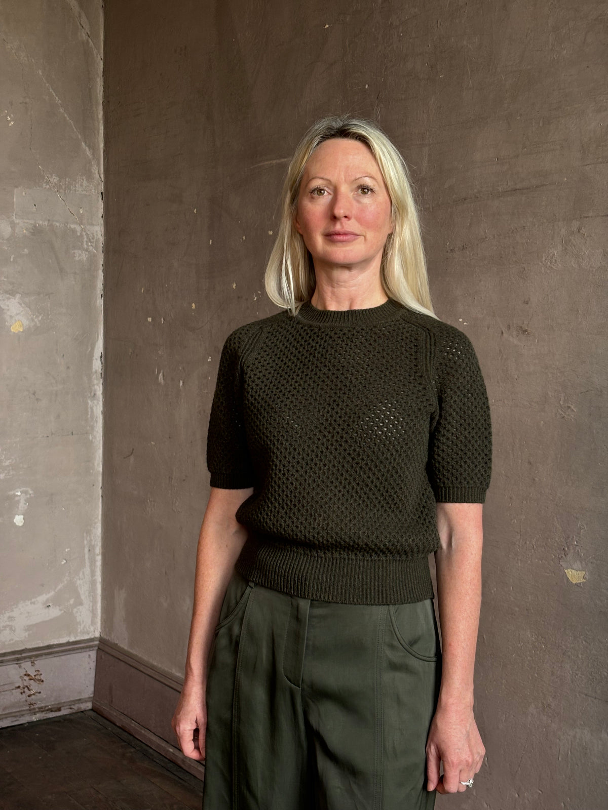Mature woman wearing designer Ulla Johnson Imara Short Sleeve dark green Sweater with a dimensional open weave