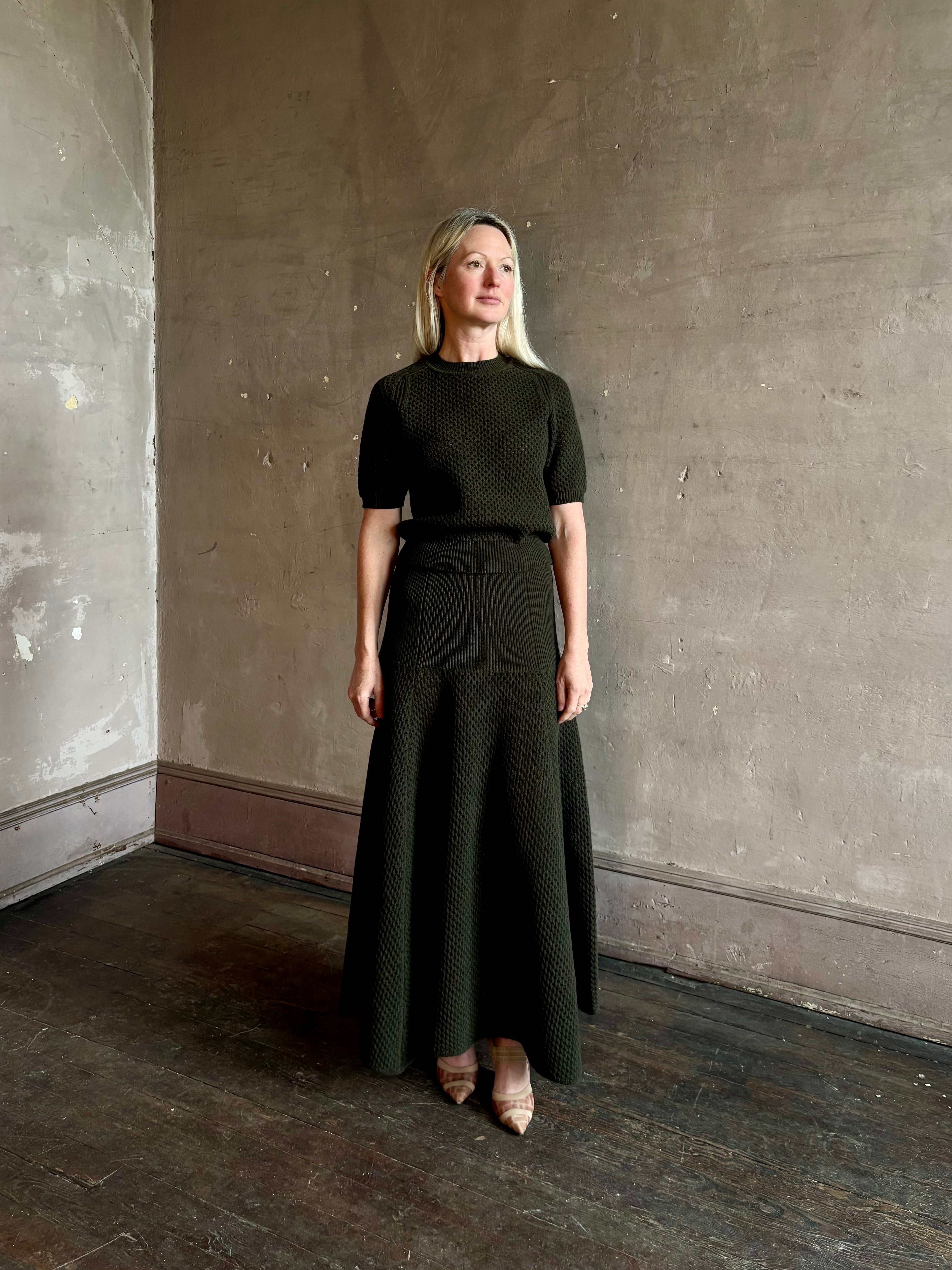 Mature woman wearing designer Ulla Johnson Lucia Wool dark green open Knit maxi Skirt with stretch waistband