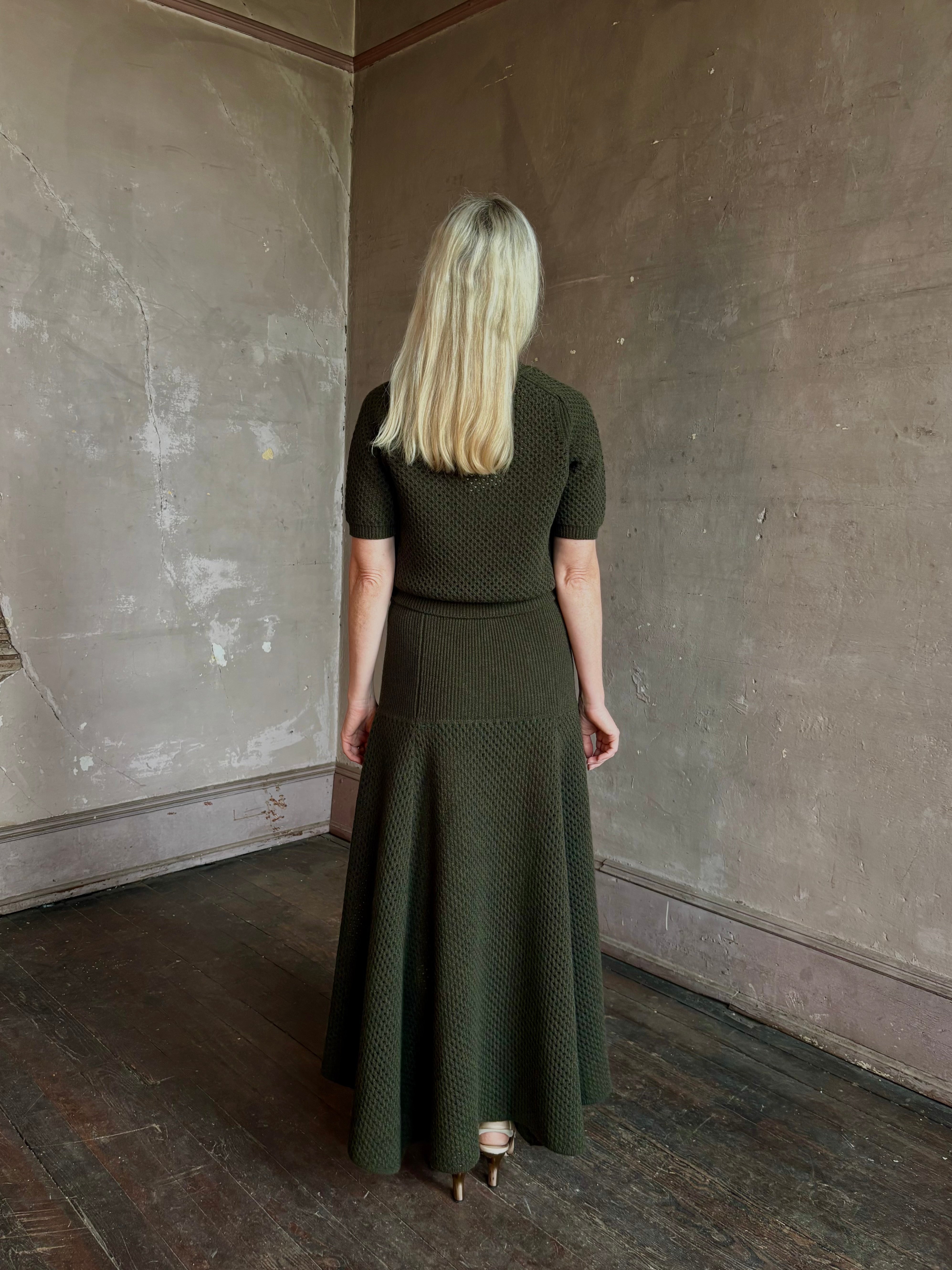 Mature woman wearing designer Ulla Johnson Lucia Wool dark green open Knit maxi Skirt with stretch waistband