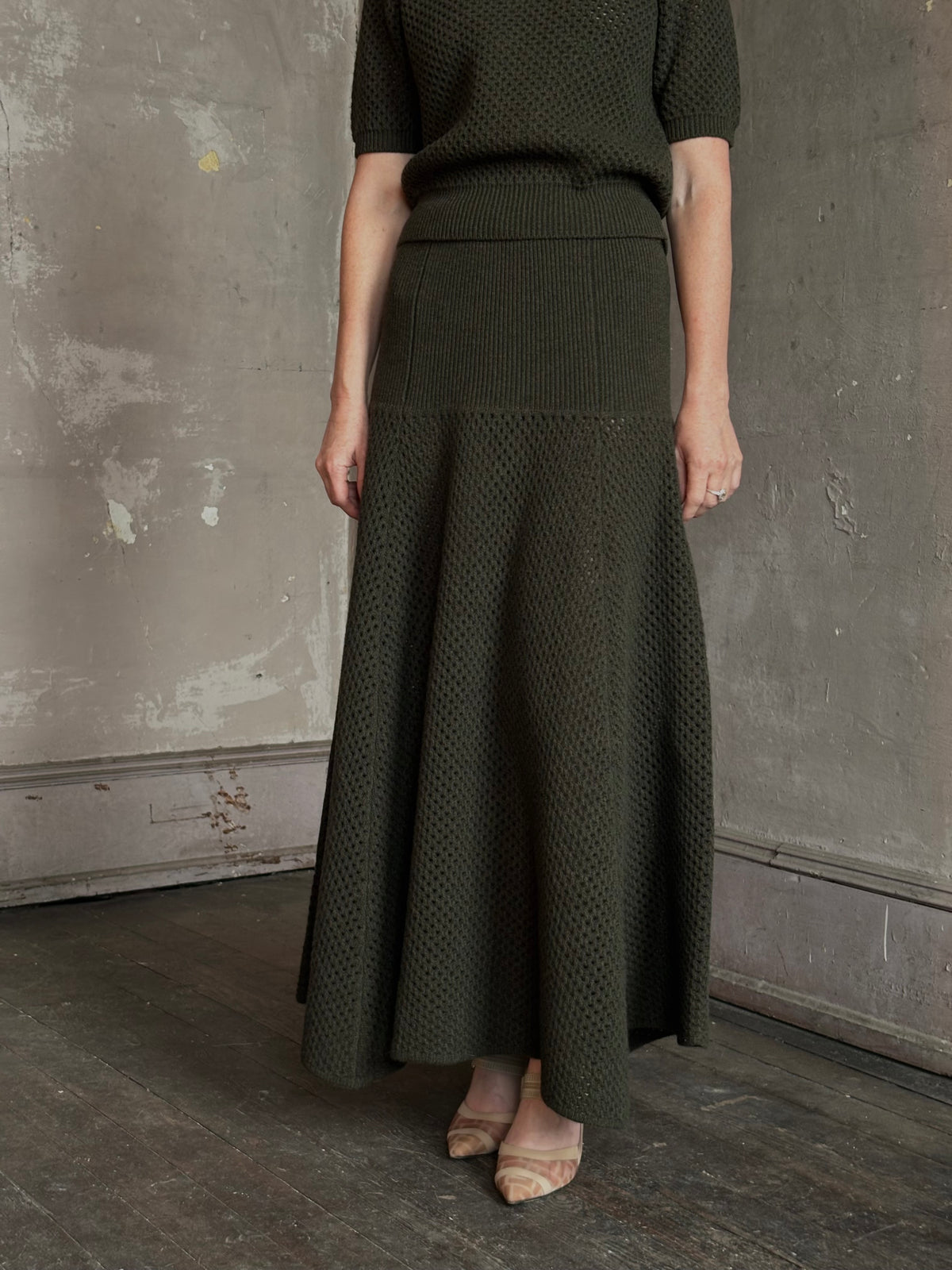 Mature woman wearing designer Ulla Johnson Lucia Wool dark green open Knit maxi Skirt with stretch waistband