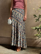 Mature woman wearing Ulla Johnson Marceline maxi knit cotton Skirt Oasis colorway navy,  aqua, and terra cotta