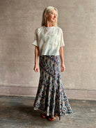 Mature woman wearing women's designer knit skirt Oasis colorway navy, cream, peach, yellow, aqua, and terra cotta