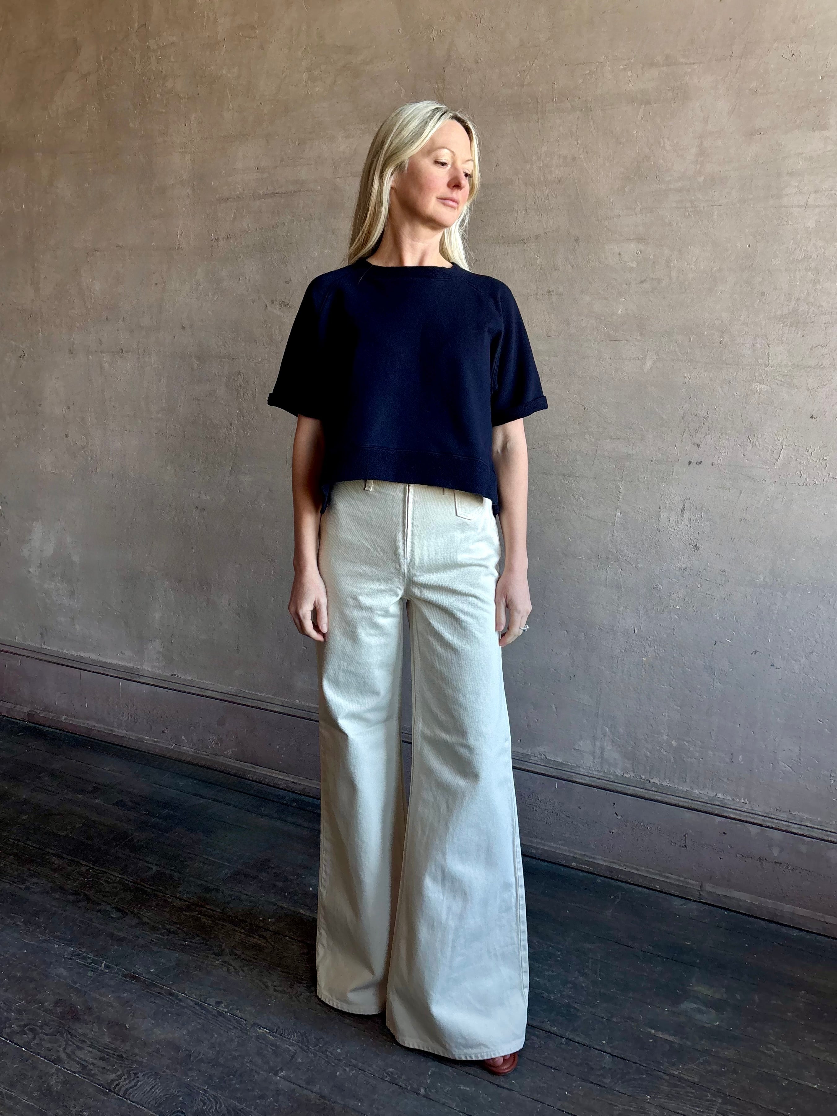 Woman wearing women's luxury designer denim by Ulla Johnson Odelia Jean handcrafted from 100% cotton in Los Angeles California with a high-rise and elegant slimmer wide leg