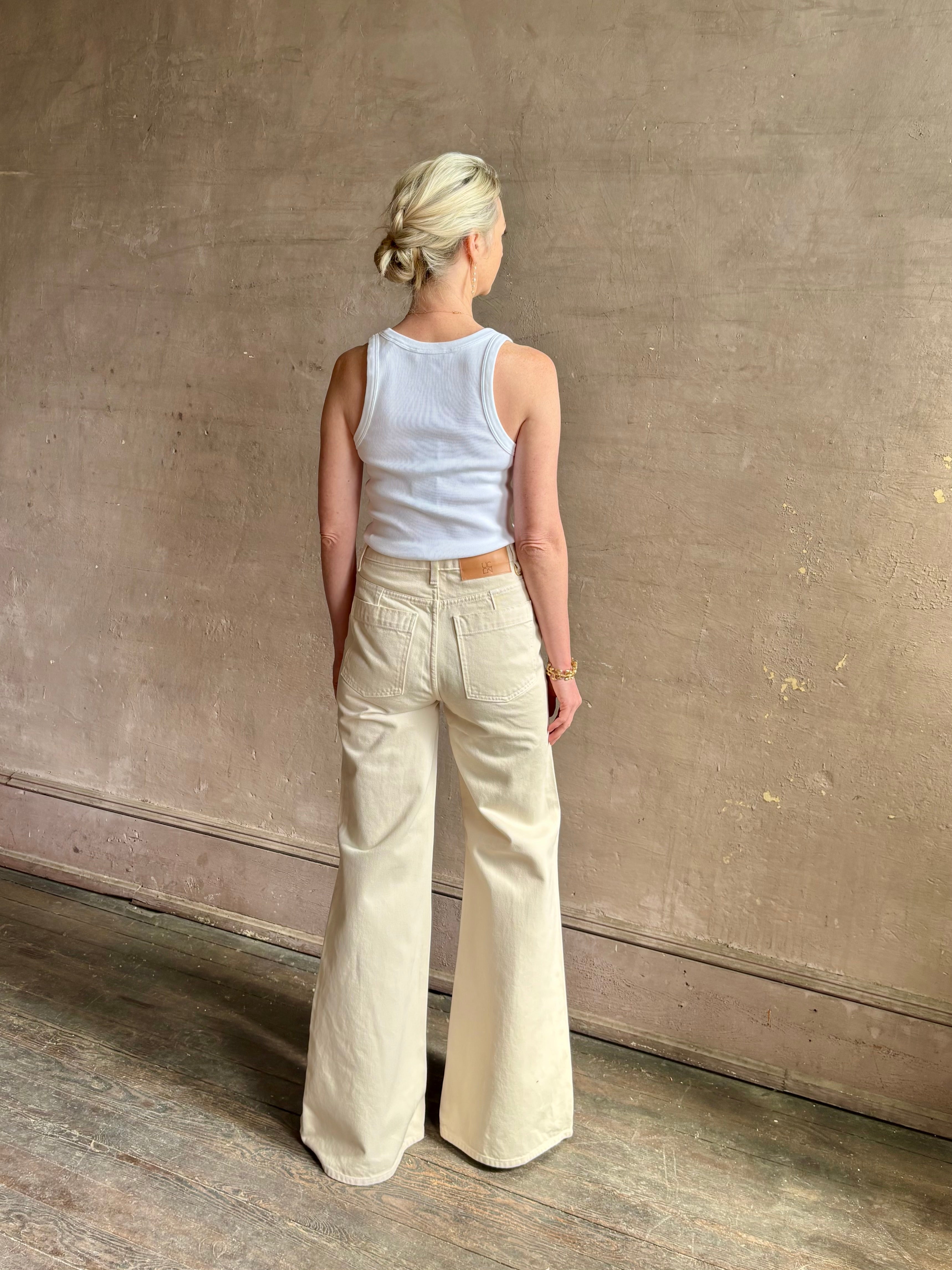 Woman wearing women's luxury designer denim by Ulla Johnson Odelia Jean handcrafted from 100% cotton in Los Angeles California with a high-rise and elegant slimmer wide leg