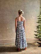 Mature woman wearing Ophelia Cami Cotton maxi Dress from Ulla Johnson rendered in a crisp white ground adorned with a soft black and light blue print and crafted from a cotton and viscose blend with an empire waist, sweatheart neckline and spaghetti straps