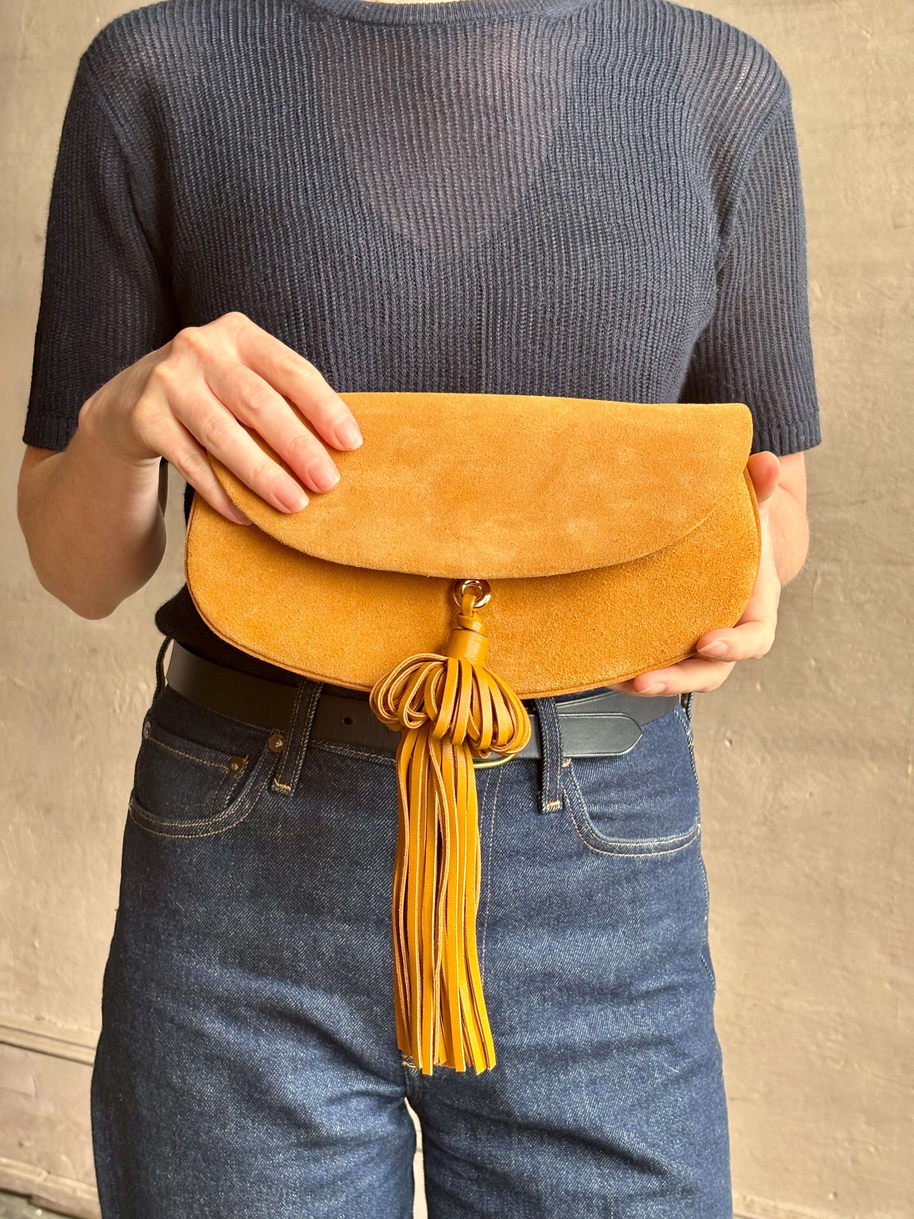 Mature woman with the luxury Italian leather  Paloma handbag with Tassel Flap from Ulla Johnson rendered in a rich caramel brown featuring a pull tassel magnetic snap closure and removable adjustable handle that seamlessly converts to a designer clutch