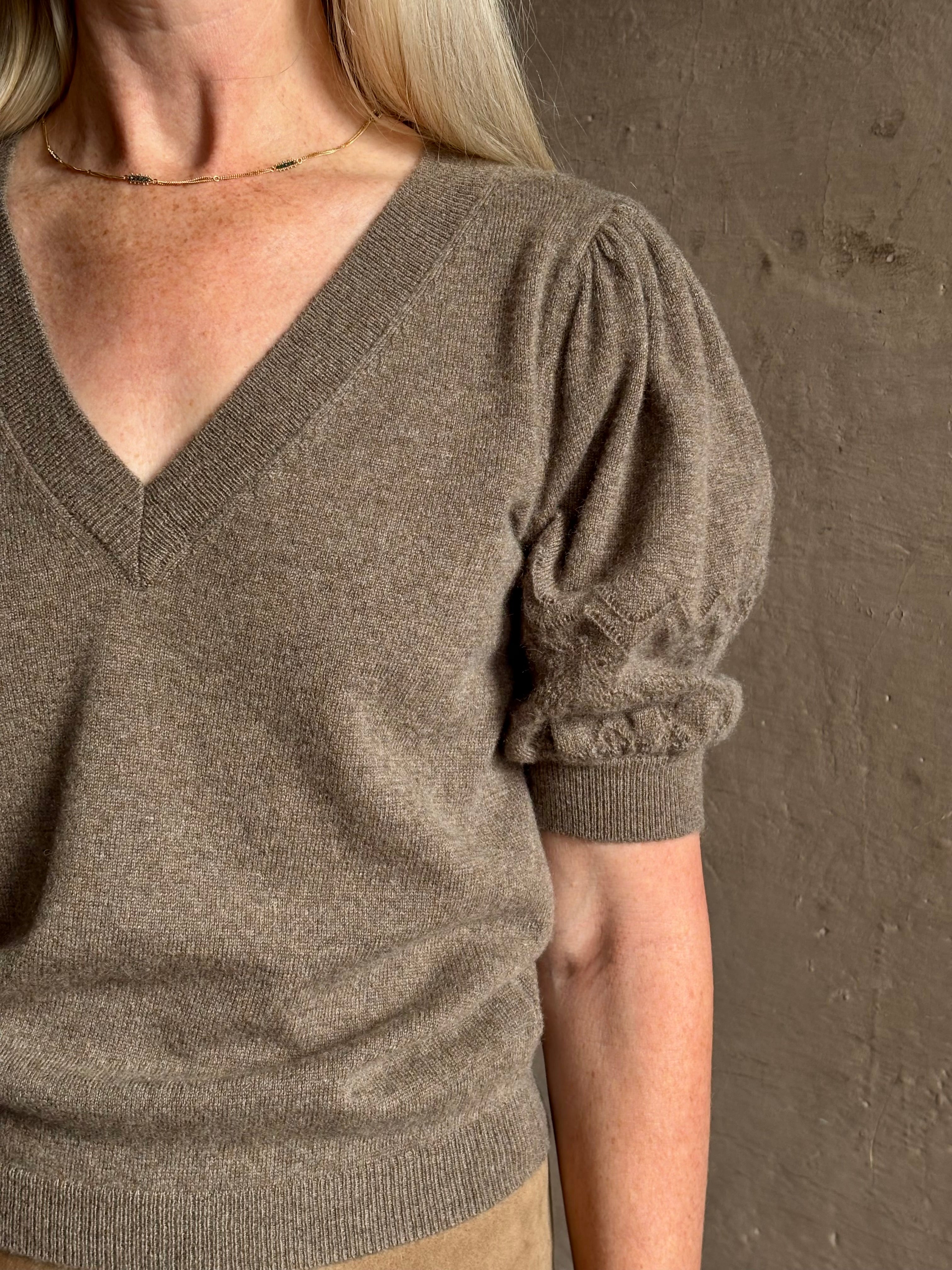 Mature woman wearing Ulla Johnson Reina v-neck driftwood brown short sleeve iIntricate Woven Sleeve Detail