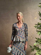 Mature woman wearing premium cotton ULLA JOHNSON Rosalia Peplum Knit Top Oasis long sleeves v-neck