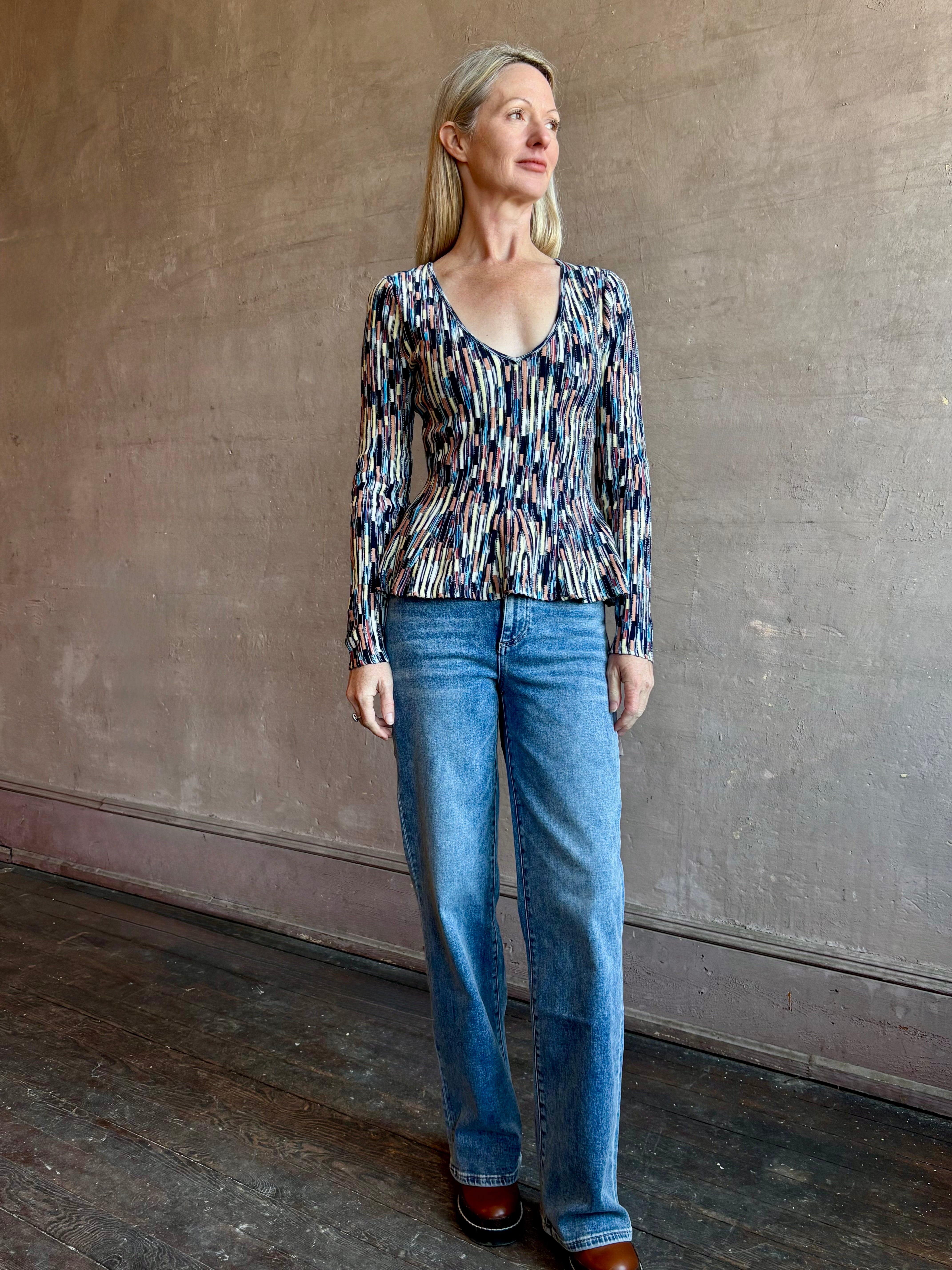 Image of woman wearing premium cotton ULLA JOHNSON Rosalia Pullover Peplum Knit Top in Oasis with long sleeves and v-neck