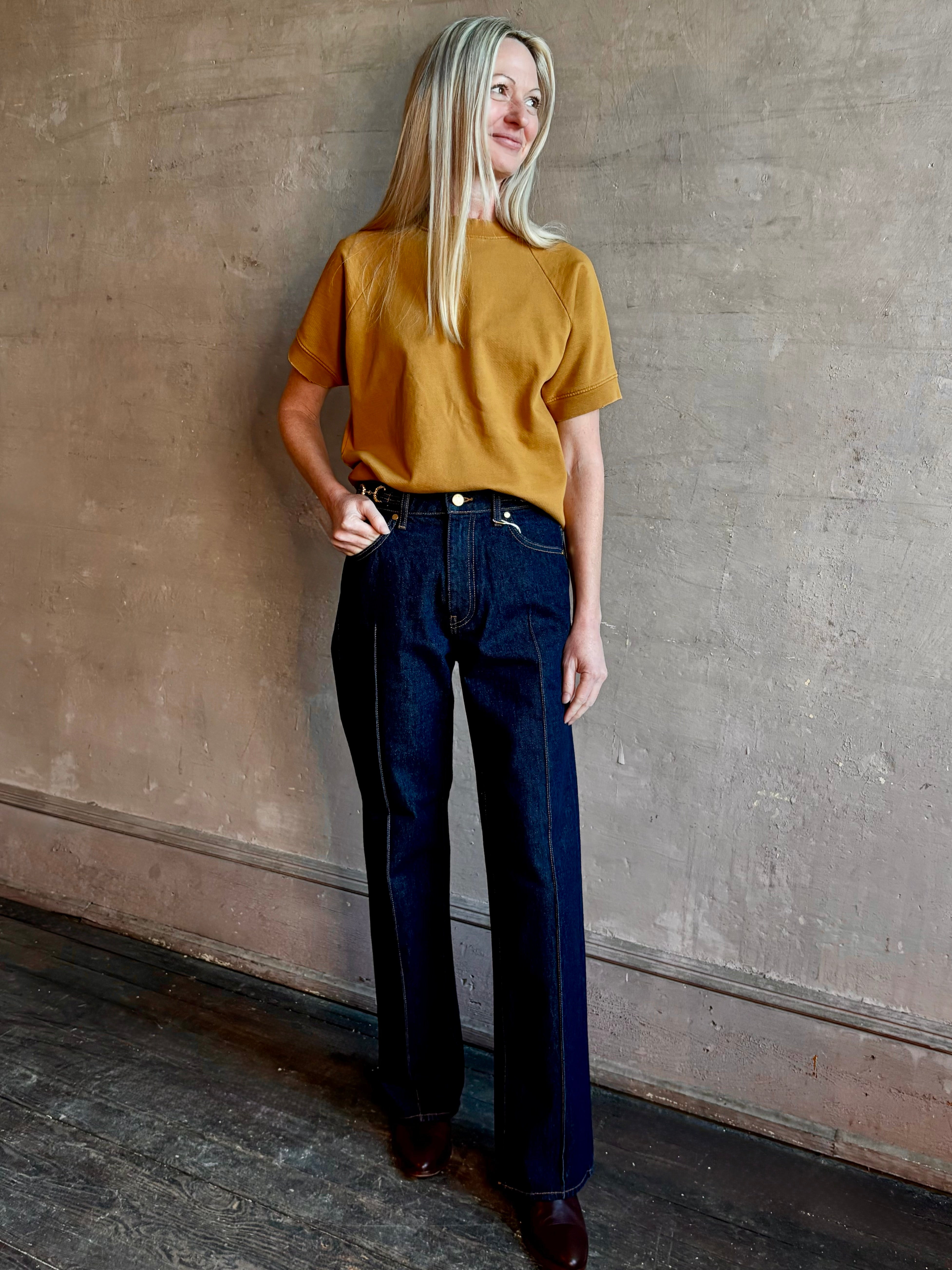 Woman wearing ULLA JOHNSON handmade Agatha Straight Leg Pintuck Rigid Denim jean in Tigris wash with horsebit detail 