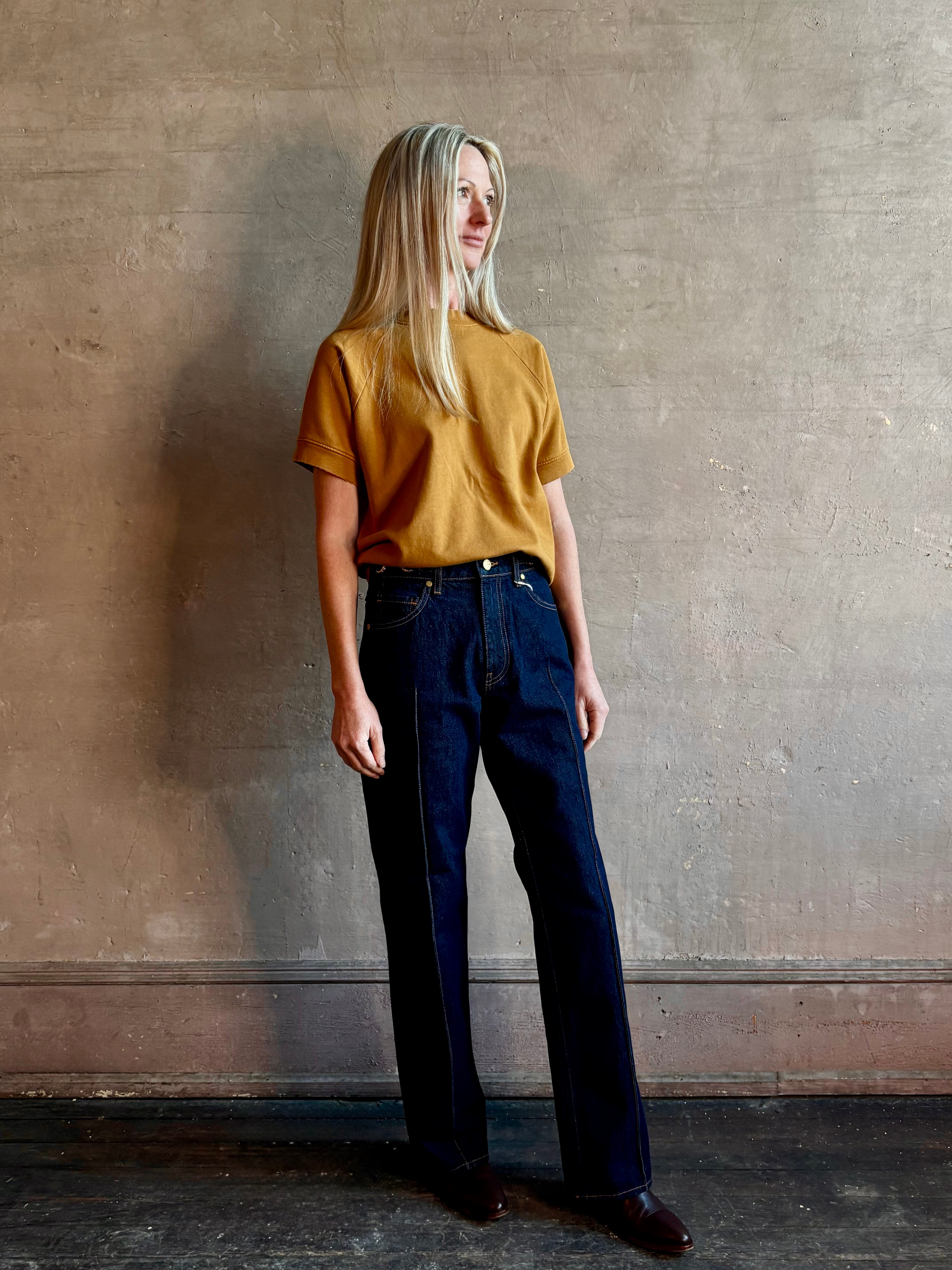 Woman wearing ULLA JOHNSON handmade Agatha Straight Leg Pintuck Rigid Denim jean in Tigris wash with horsebit detail 