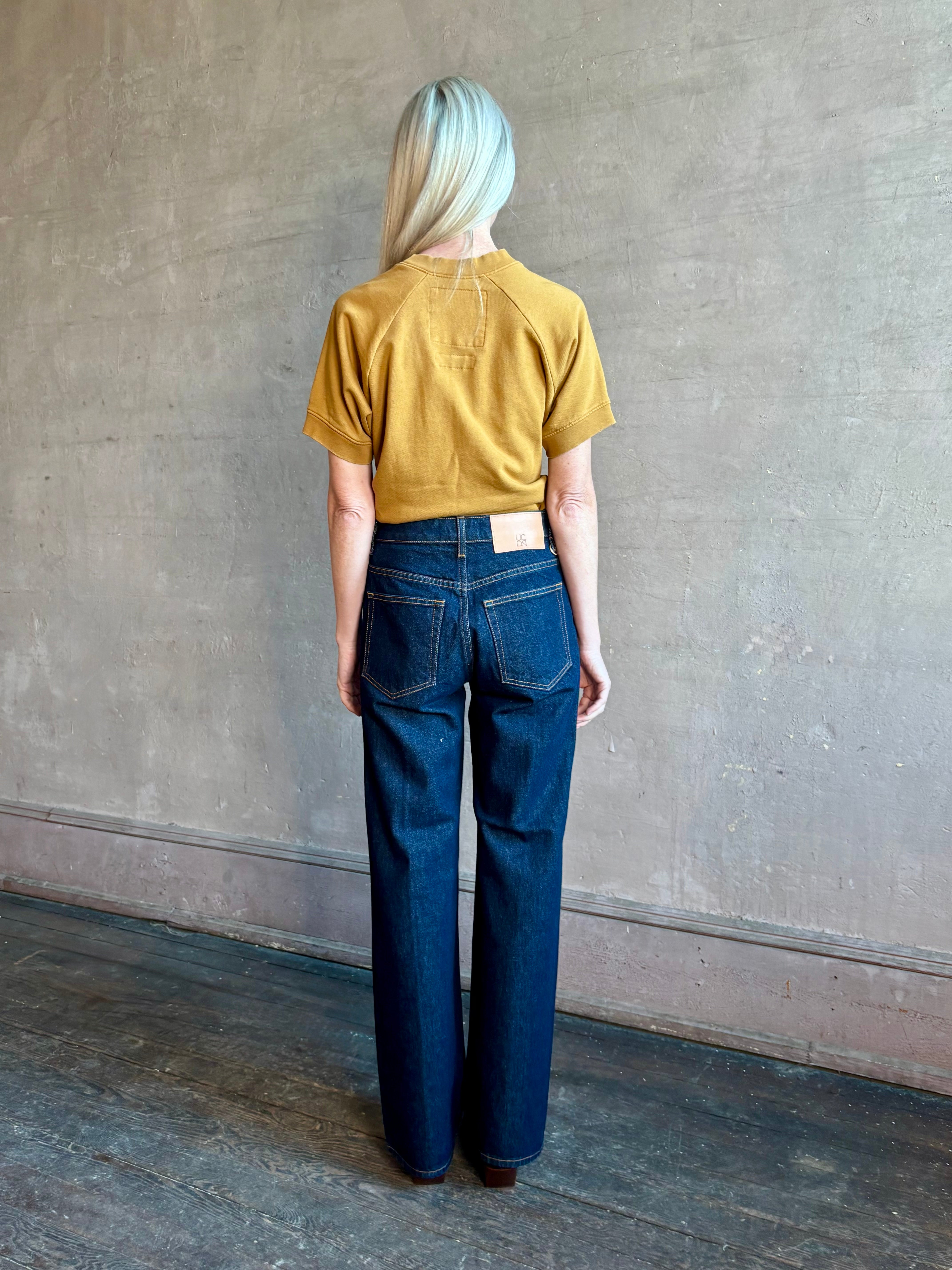 Woman wearing ULLA JOHNSON handmade Agatha Straight Leg Pintuck Rigid Denim jean in Tigris wash with horsebit detail 