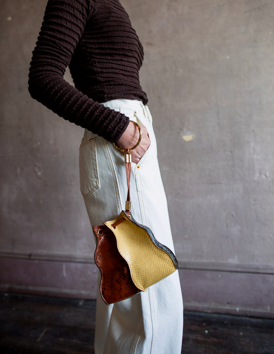 Image featuring woman wearing the Adria by Ulla Johnson in snakeskin embossed leather, drawstring closure, crossbody strap and bracelet handle.