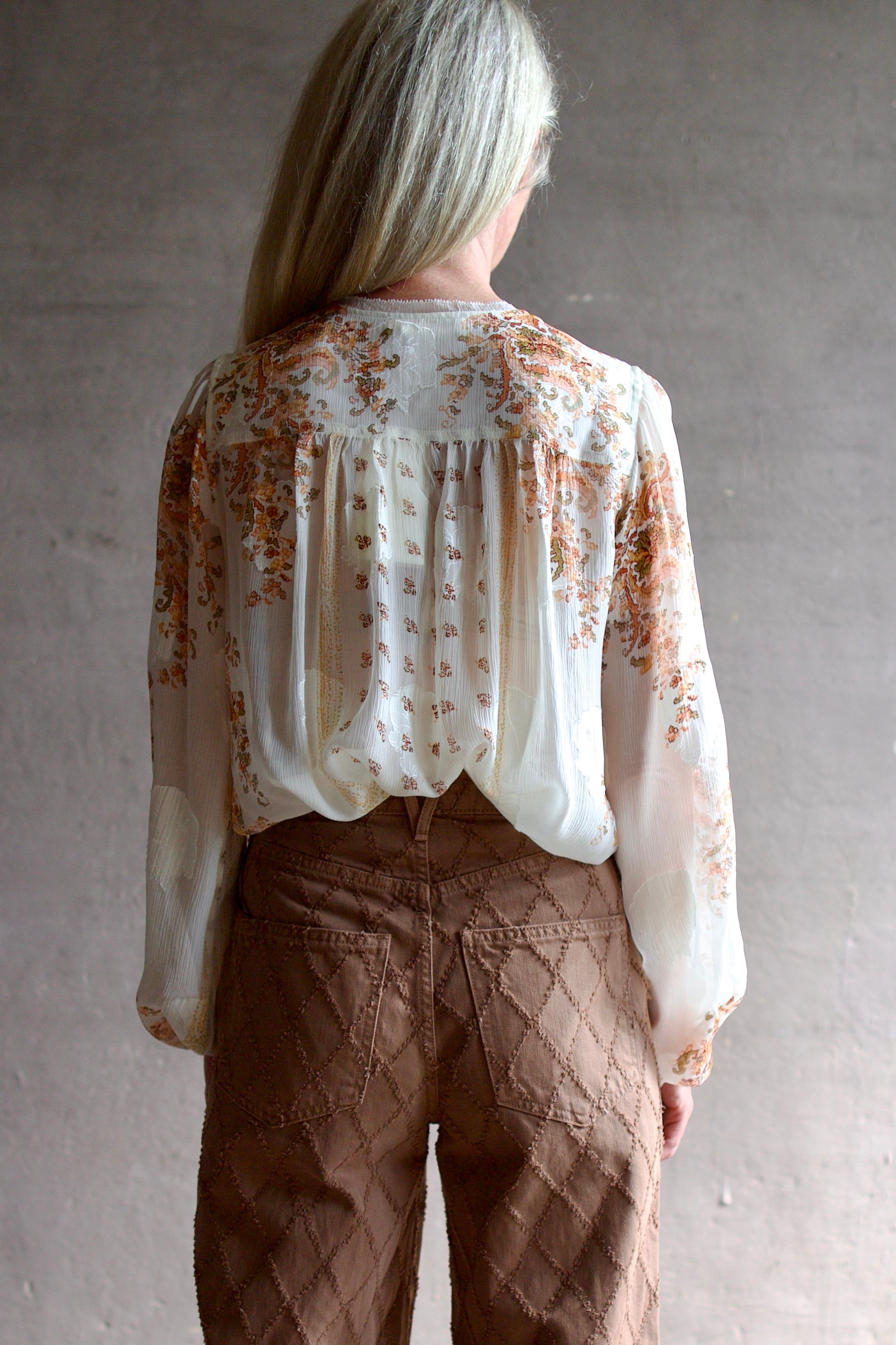 Model wearing luxury designer Ulla Johnson Aster Blouse in alabaster colorway and airy silk chiffon fabric with an elegant boho inspiration