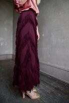 Mature Woman wearing designer Ulla Johnson's Astrid Knit Maxi Skirt in Mahogany knit with fringe detailing 