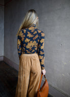 image of the back of a woman wearing the Ulla Johnson Aurelia turtleneck, forte forte matte corduroy pants and Ulla Johnson Twyla handbag